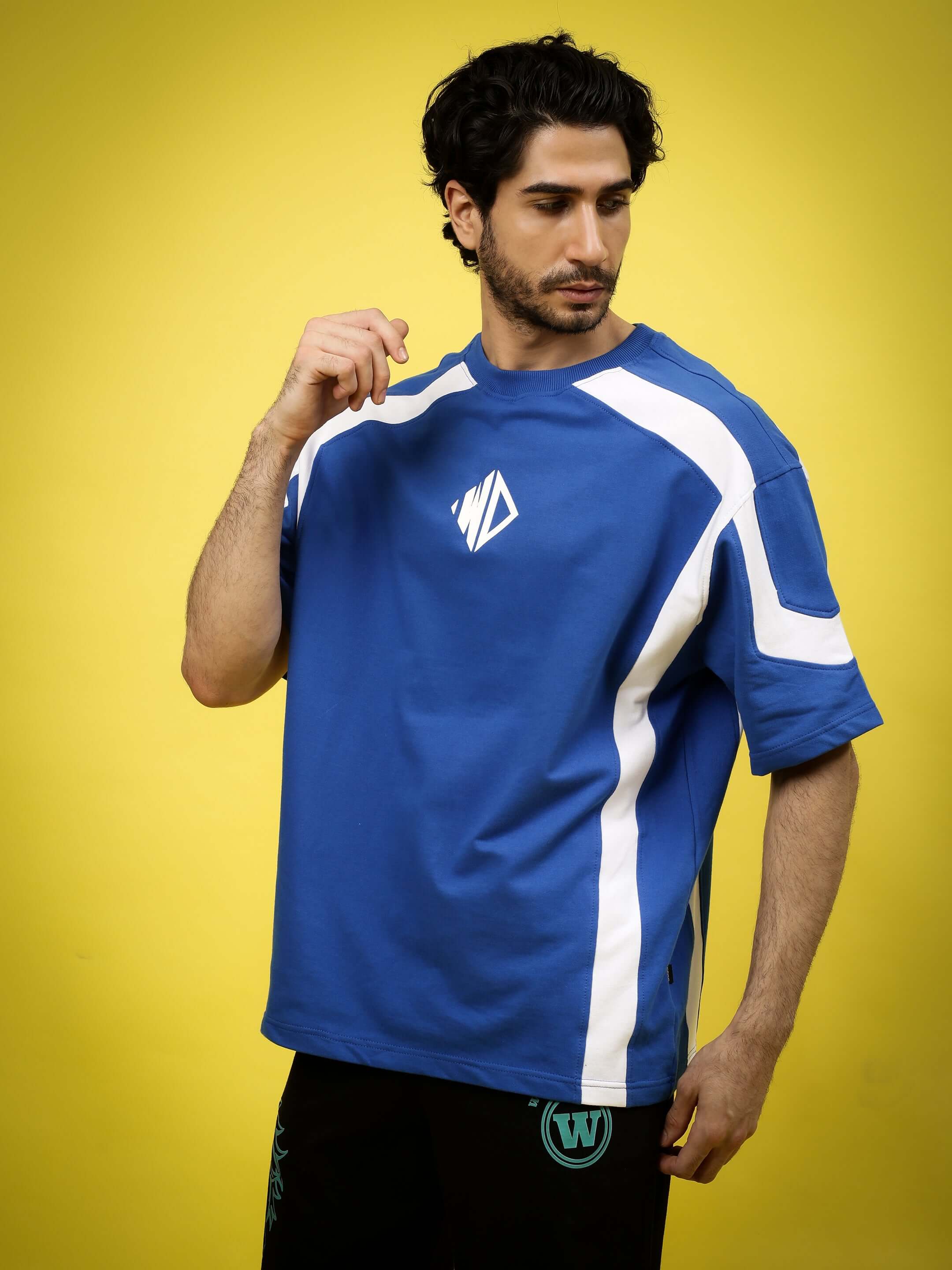 Model wearing royal blue oversized rugby t-shirt with white stripes, made of premium cotton French terry, against yellow background.