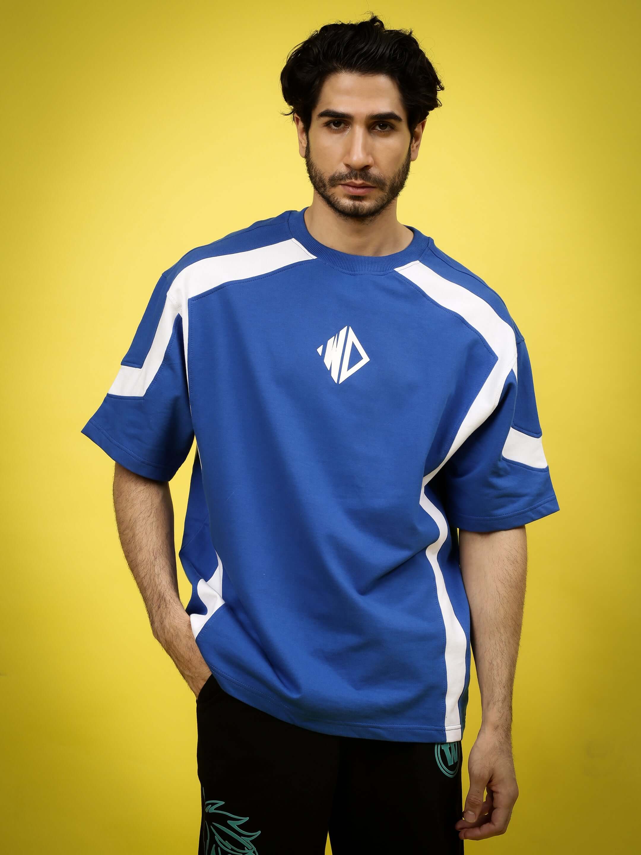 Model wearing a royal blue and white oversized rugby T-shirt made from premium cotton French terry fabric, front view on yellow background.