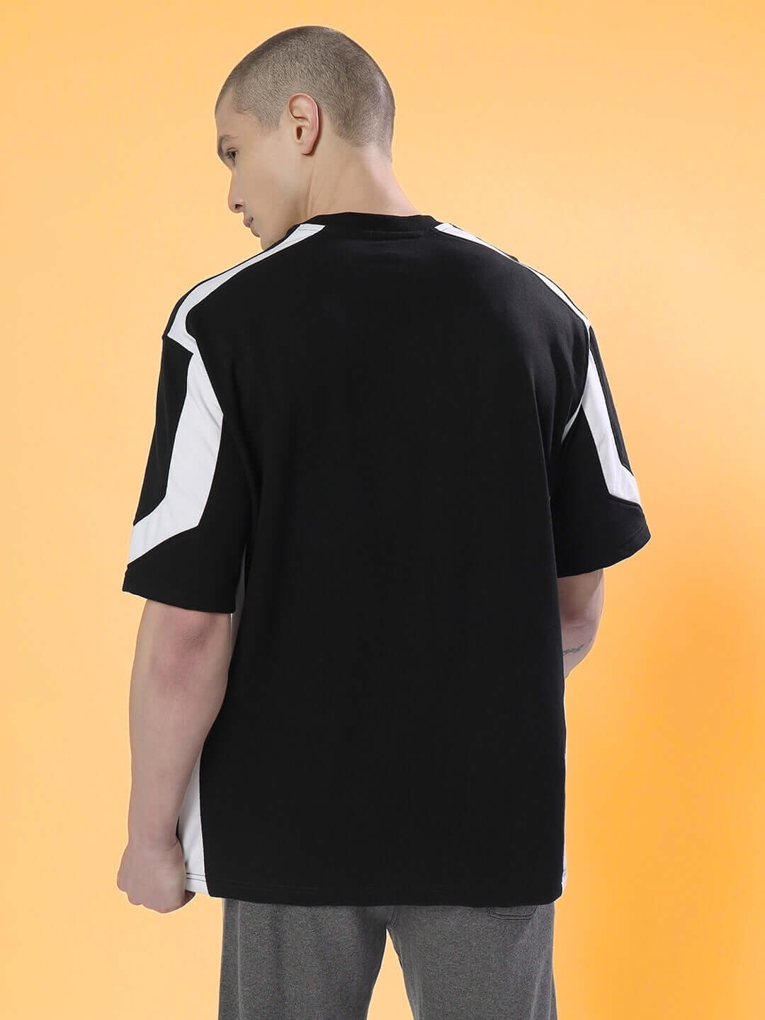 Back view of a model wearing a black and white rugby over-sized T-shirt made from premium cotton French terry fabric, showcased in a casual pose.