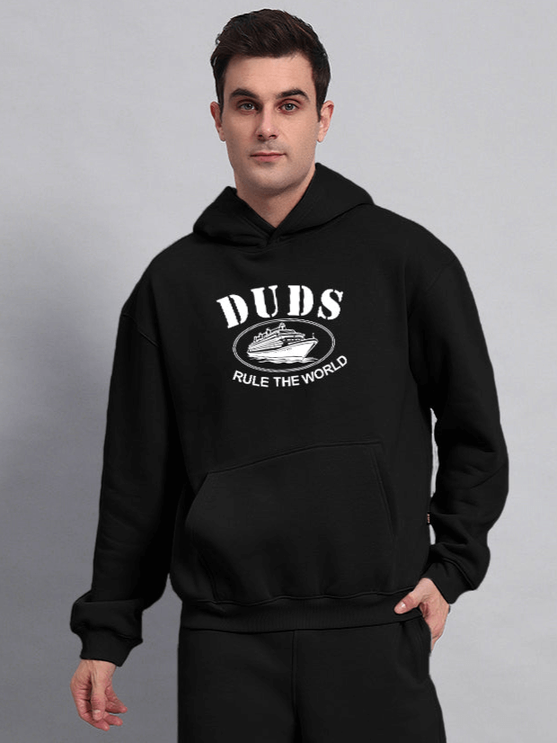 RULE THE WORLD OVERSIZED HOODIE BLACK - Model wearing black oversized hoodie with front graphic and slogan, showcasing streetwear style.