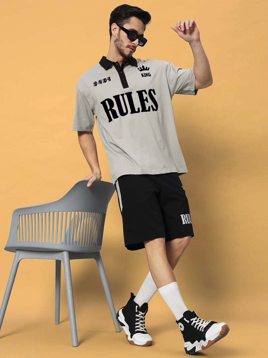 Man wearing grey-black Rules King Co-ord Set, standing stylishly beside a chair, showcasing premium cotton French Terry fabric.