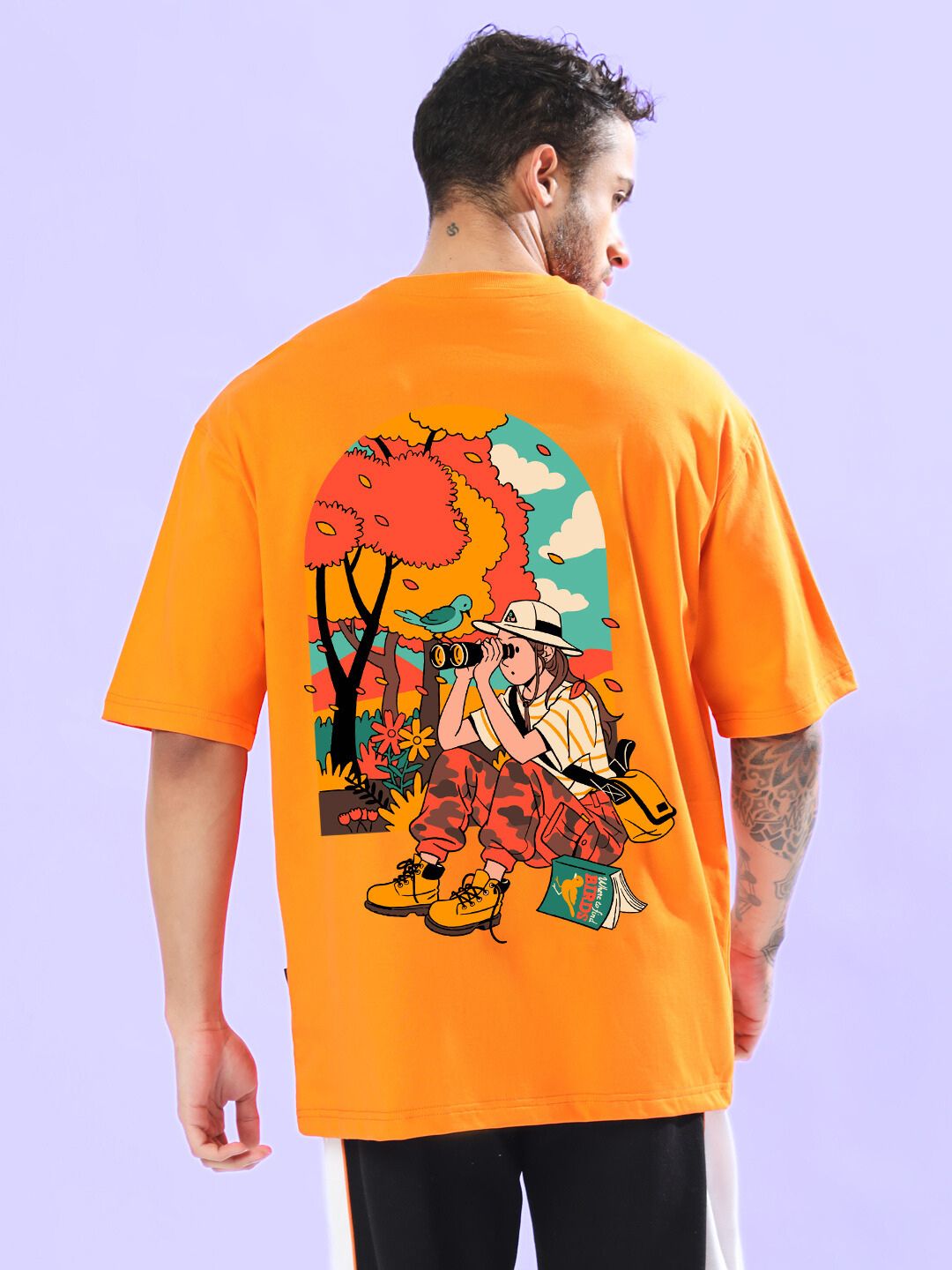 Man wearing SAFARI PRINTED OVERSIZED T-SHIRT ORANGE with graphic design.
