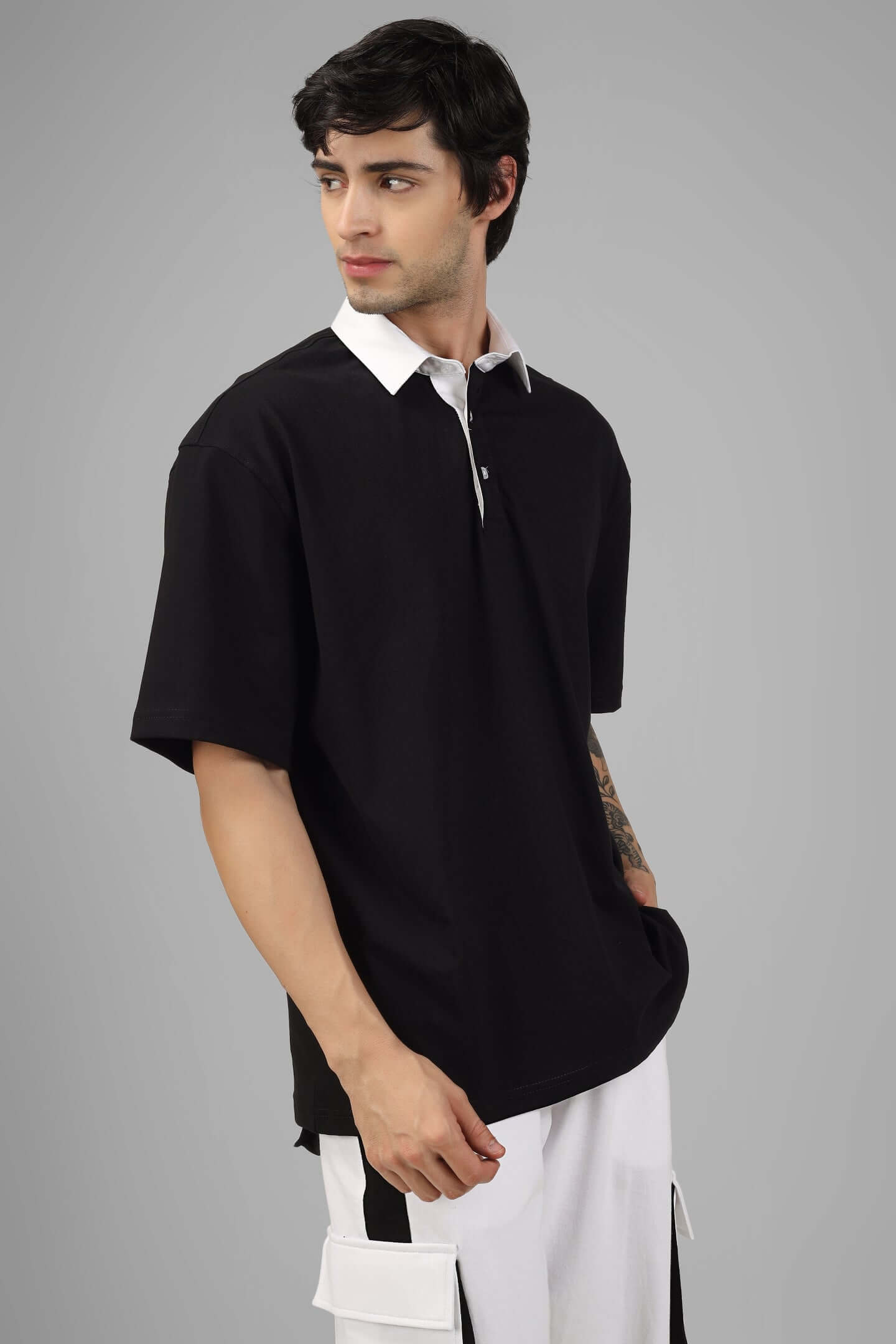Model wearing SAGOL Polo oversized black T-shirt, half sleeves, white collar; premium 100% cotton fabric, showcasing comfortable fit.