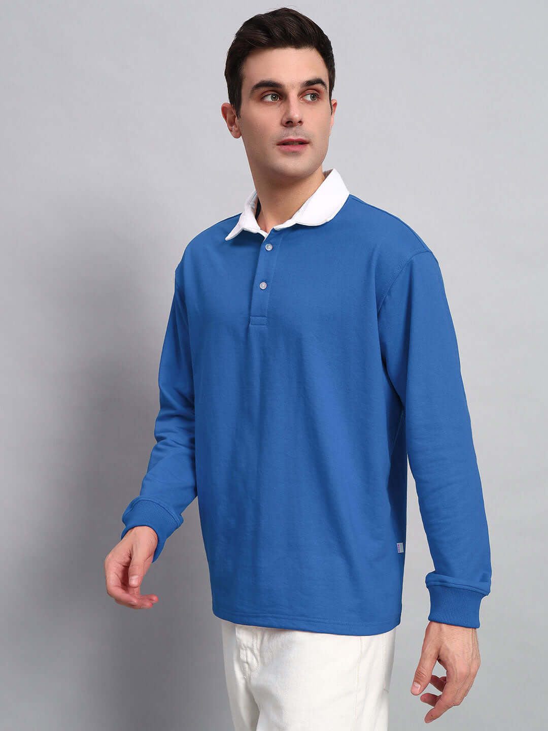 Model wearing blue oversized polo sweatshirt with white collar, made of 97% cotton French terry and 3% elastane, bio-washed.