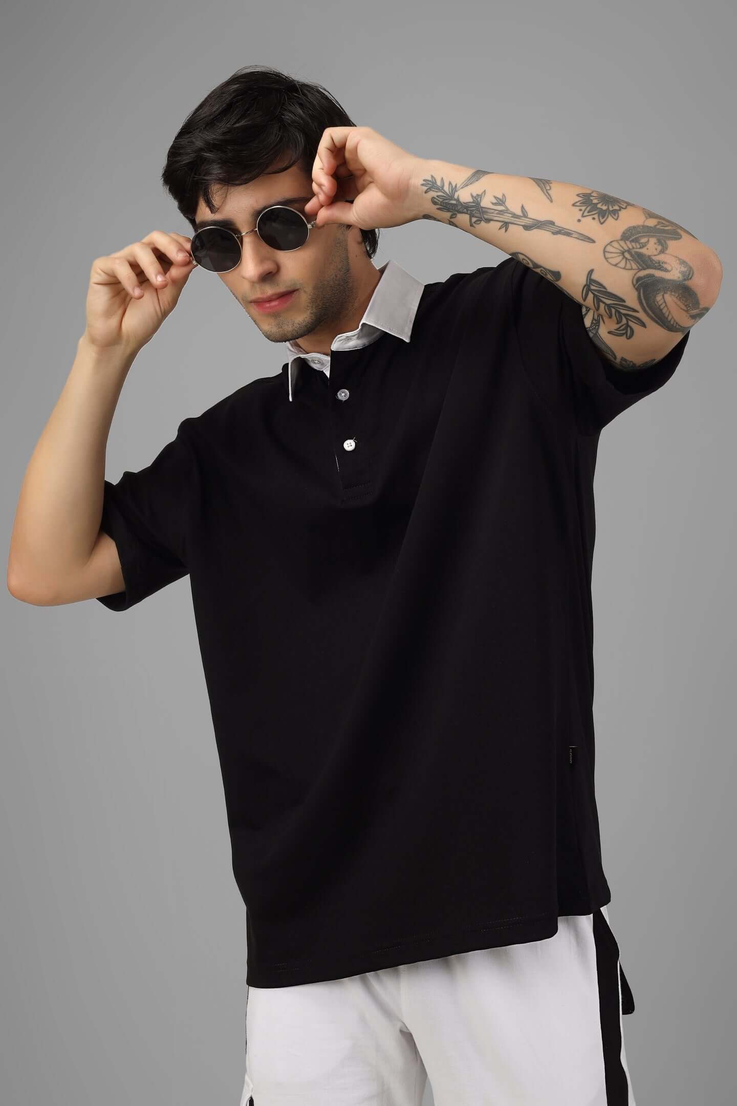 Model wearing SAGOL oversized black polo t-shirt in premium 100% cotton, styled with sunglasses, highlighting casual chic aesthetic.