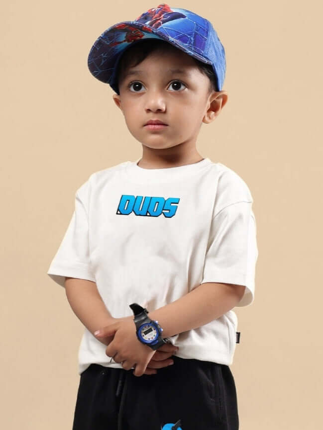 Child wearing SAMURAI OVERSIZED T-SHIRT FOR BOYS & GIRLS OFF WHITE with blue cap and wristwatch