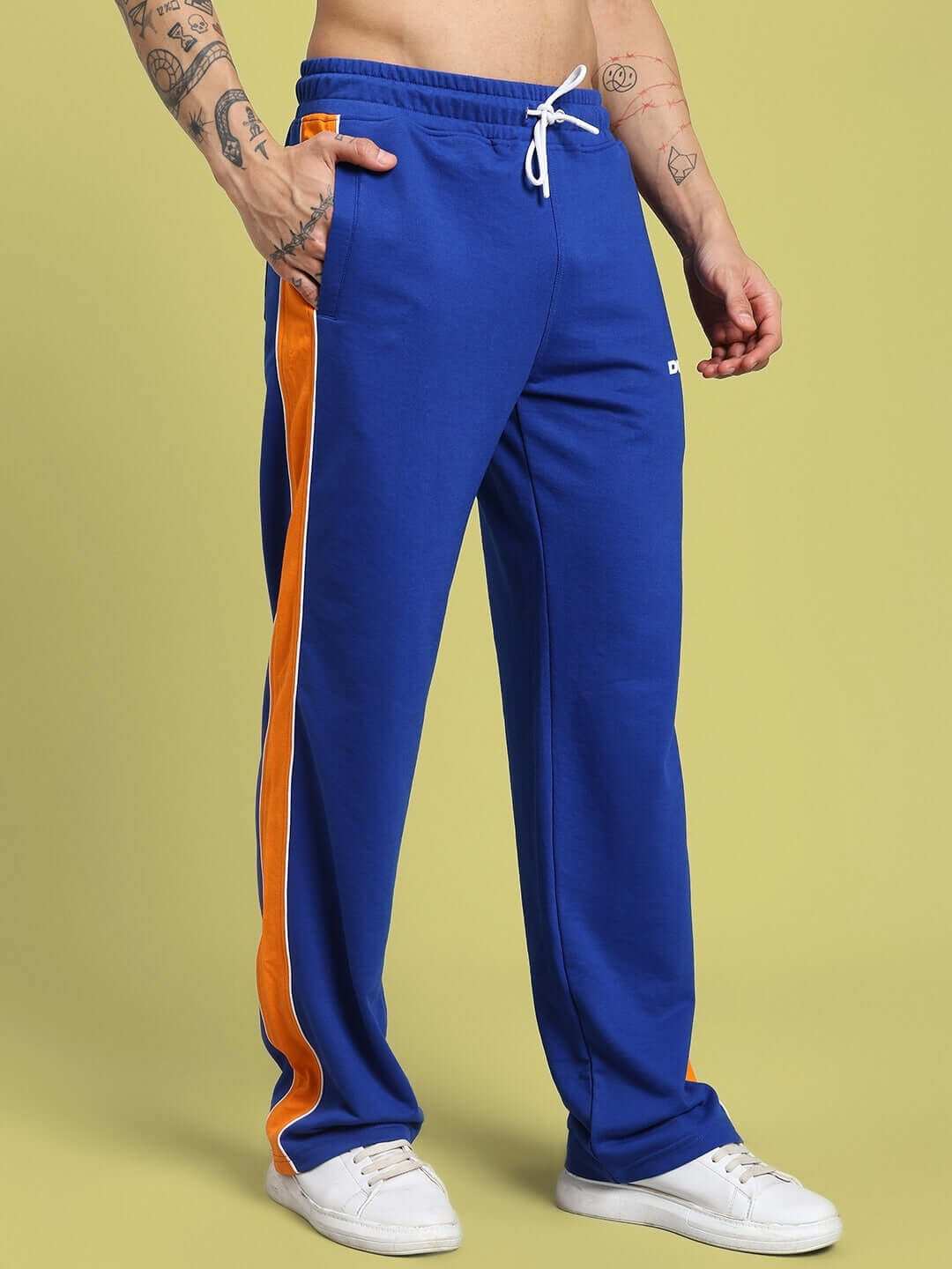Person wearing SANFORD STRIPE JOGGERS BLUE with orange stripe and drawstring, standing indoors. Athletic fit and casual style for active wear.