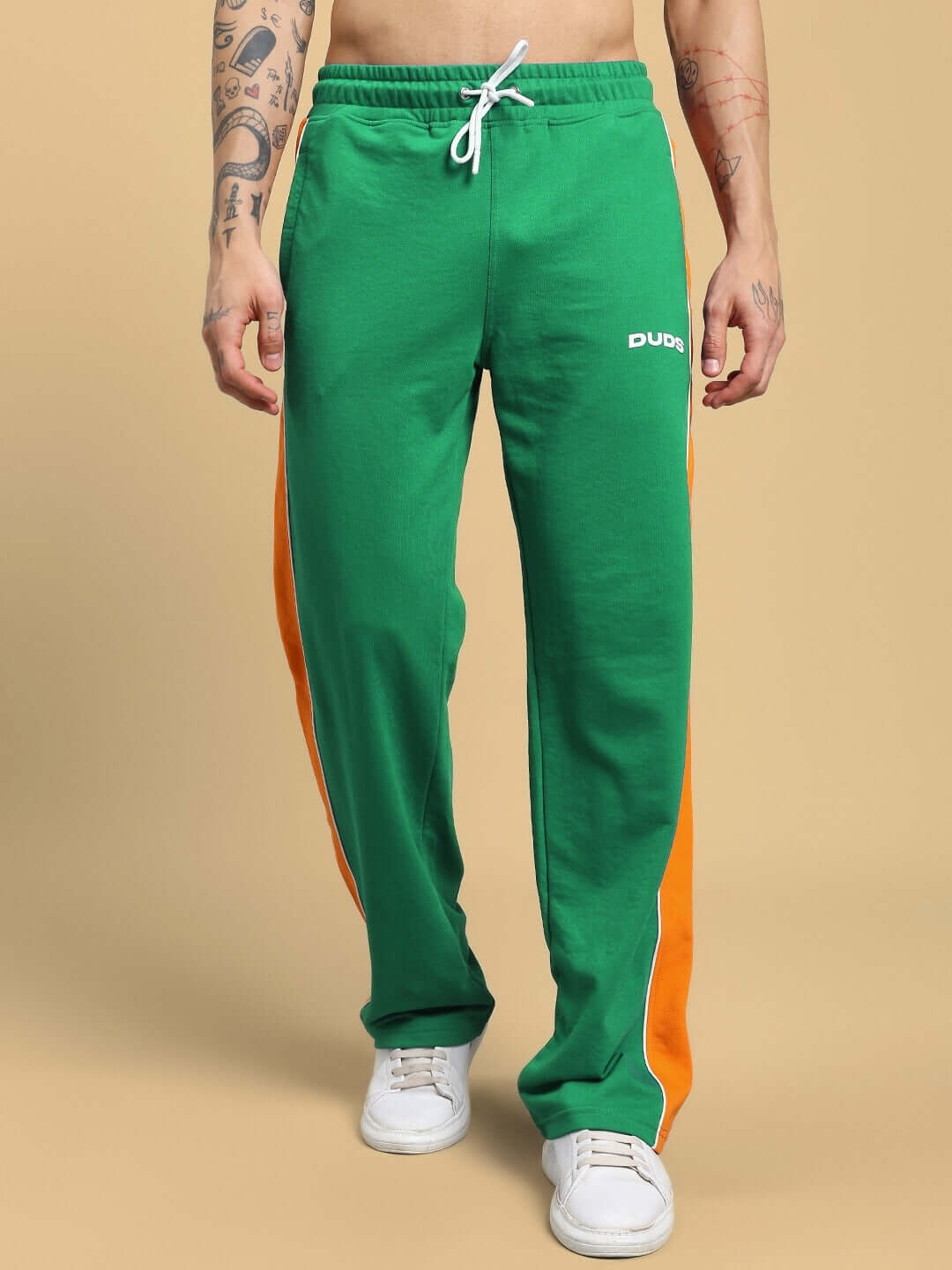 Person wearing green Sanford Stripe Joggers with orange side stripes and white sneakers, showcasing casual fashion.