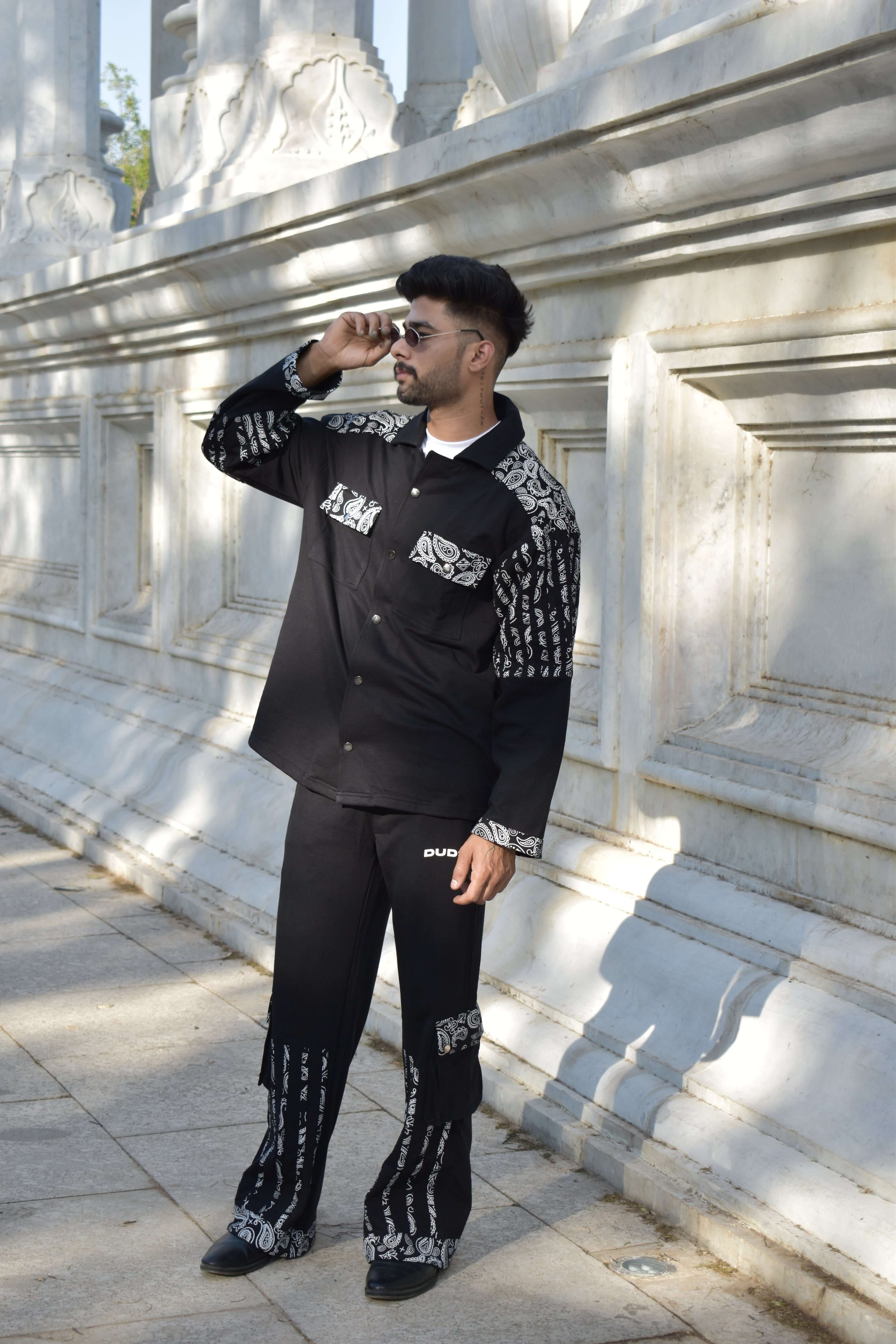 Man wearing Sanganeri black co-ord set made from 100% cotton terry fabric, standing outdoors against an elegant stone background.
