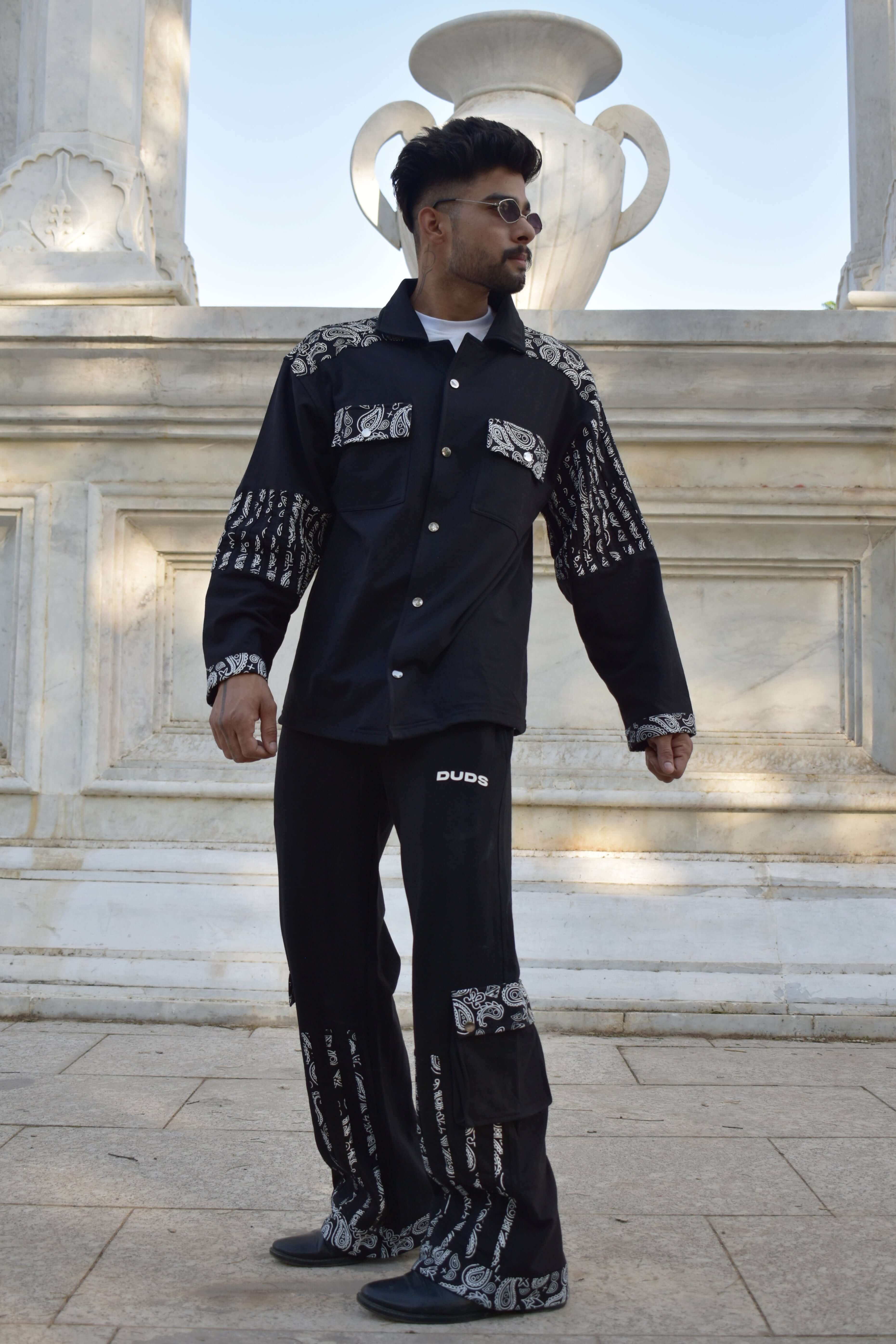 Man wearing Sanganeri co-ord set in black with intricate designs, made of premium 100% cotton terry, standing outdoors.
