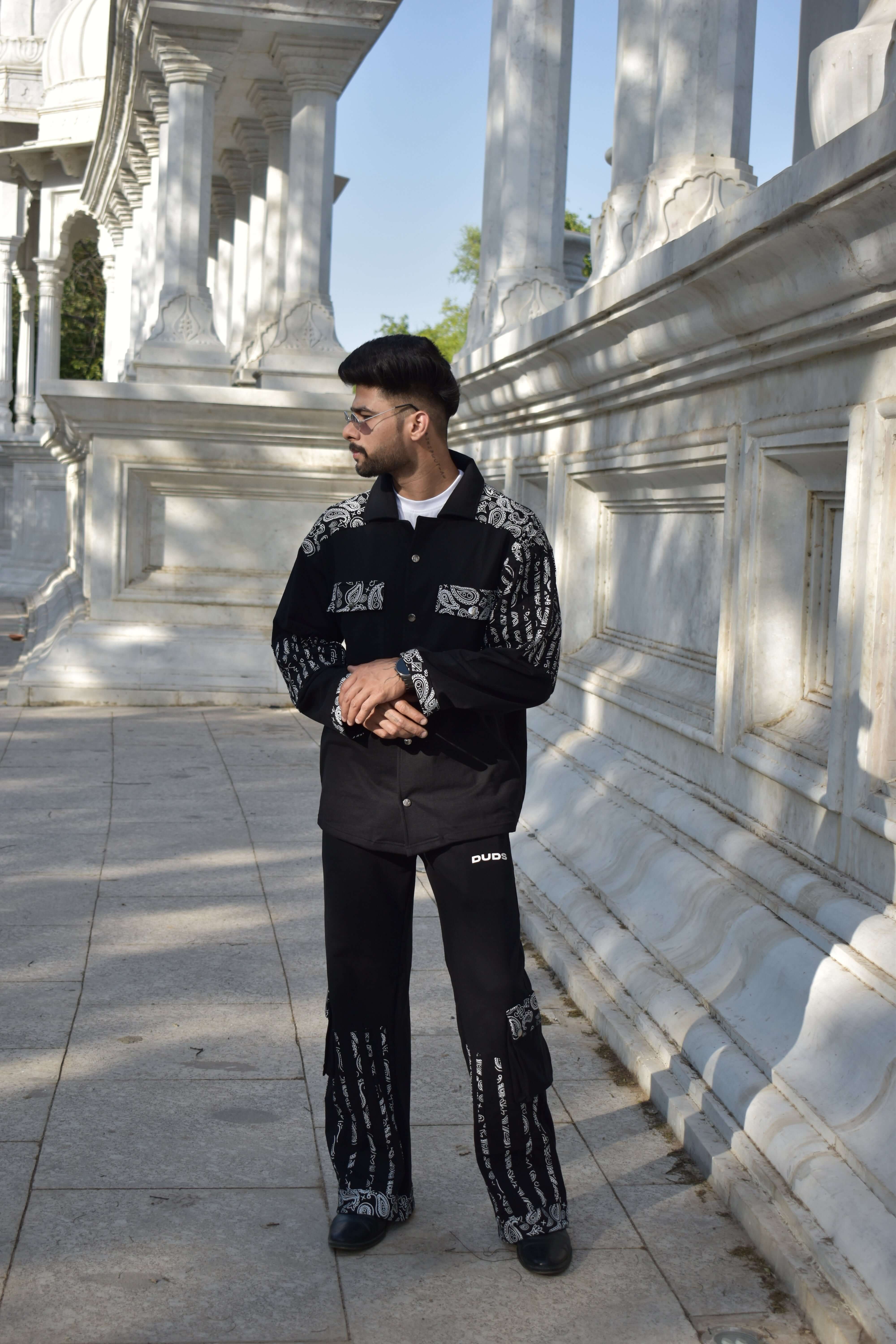 Model wearing Sanganeri black co-ord set in 100% cotton terry, designed with intricate patterns, standing in front of architectural pillars.