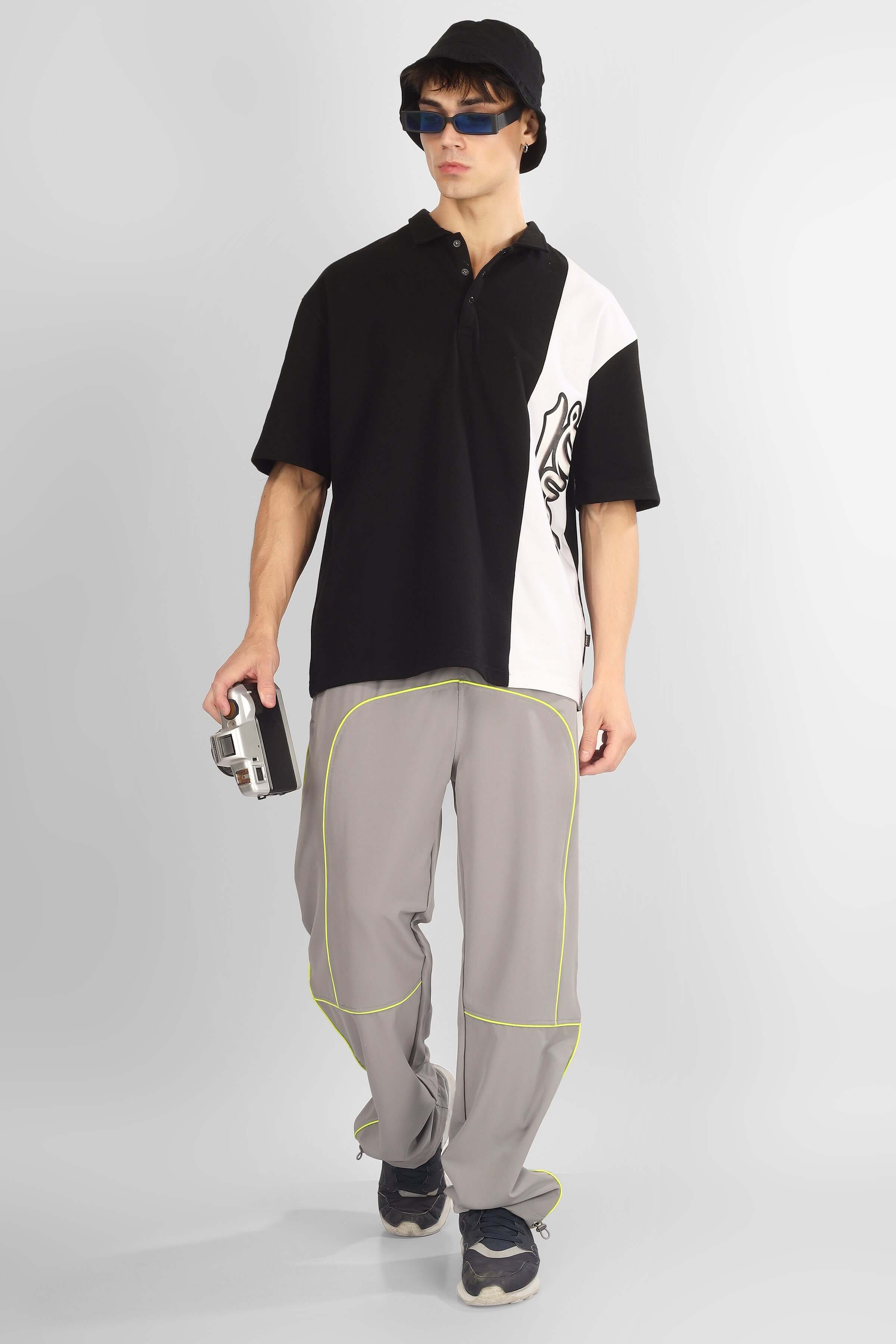 Model wearing grey scoop parachute cargo pants with black and white shirt, accessorized with sunglasses and black hat.