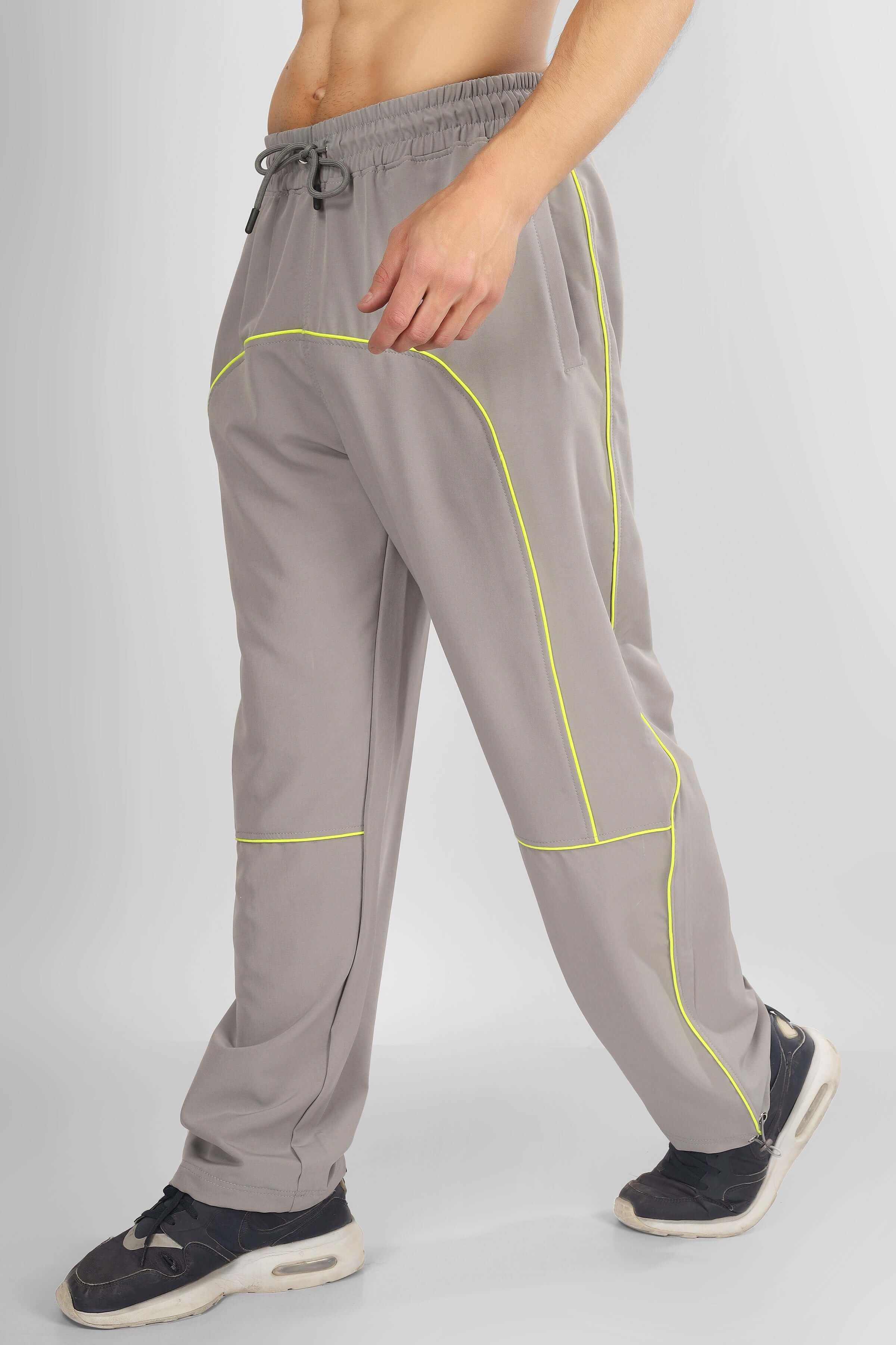 Man wearing grey scoop parachute cargo pants with neon piping detail, showcasing athletic design and relaxed fit.