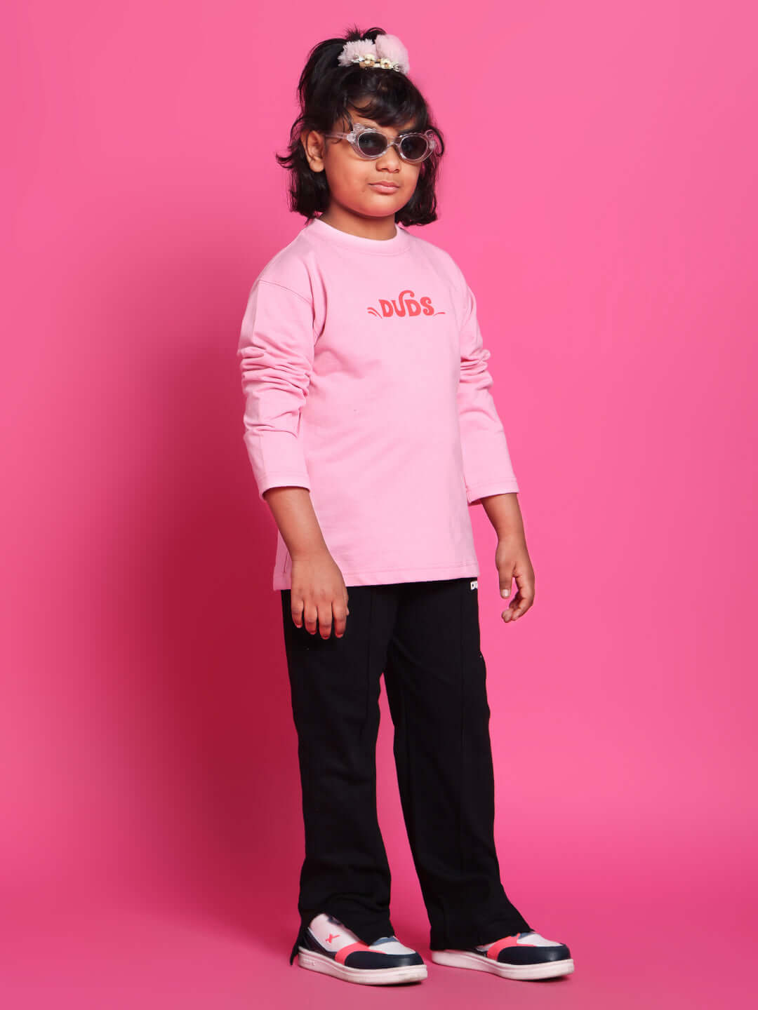 Child wearing a SCOOTER CO-ORD FOR BOYS GIRLS PINK set with sunglasses, standing stylishly.