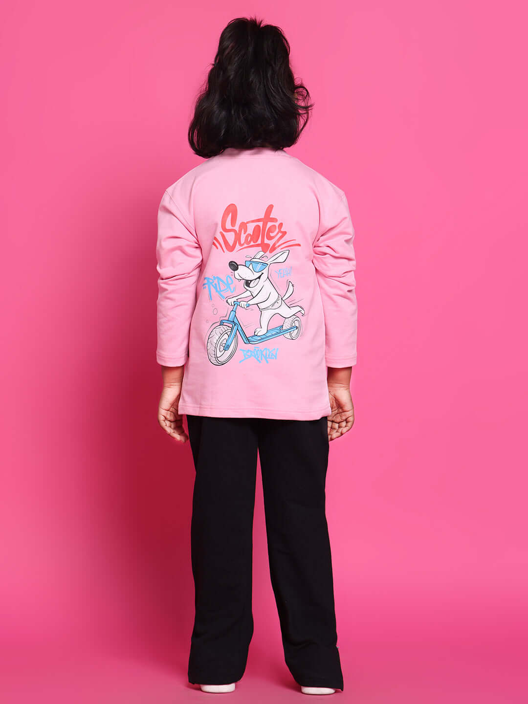 Child wearing pink Scooter Co-Ord set with graphic design, tailored for boys and girls by DUDS, standing against a pink background.