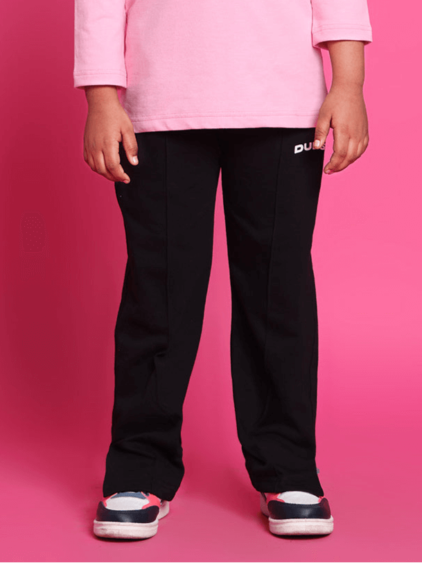 Child wearing black DUDS scooter jogger pants standing against a pink background.