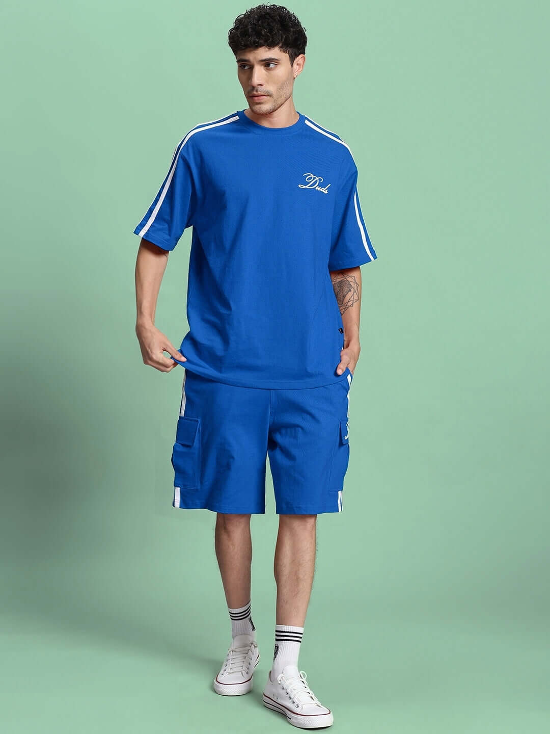 Man wearing SCOTIA REGULAR FIT SHORTS BLUE, showcasing custom fit options and stylish casual wear ensemble.