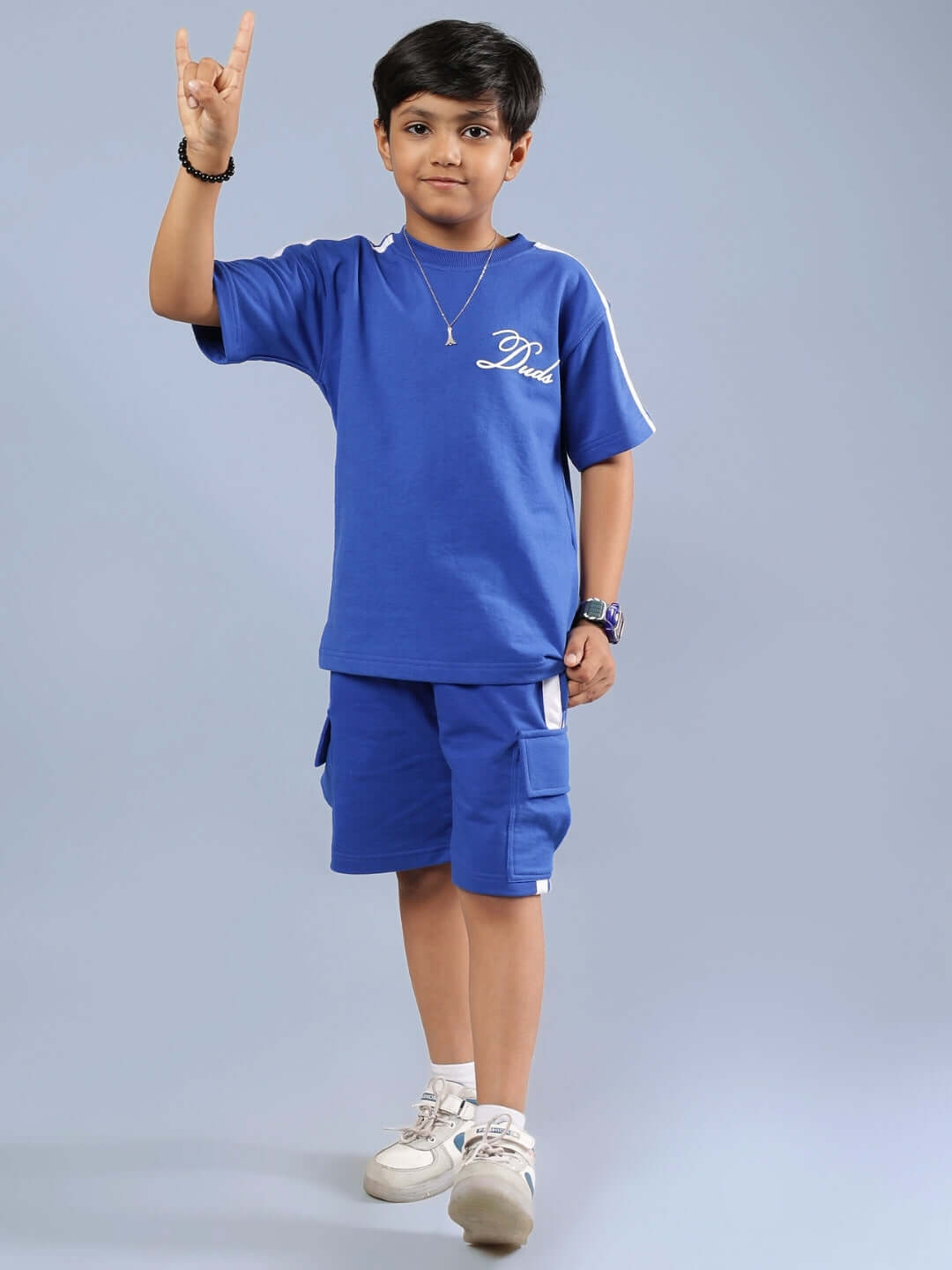 Child wearing a royal blue Scotia Summer co-ord set for boys and girls, featuring tailored design by DUDS with shorts and a t-shirt.