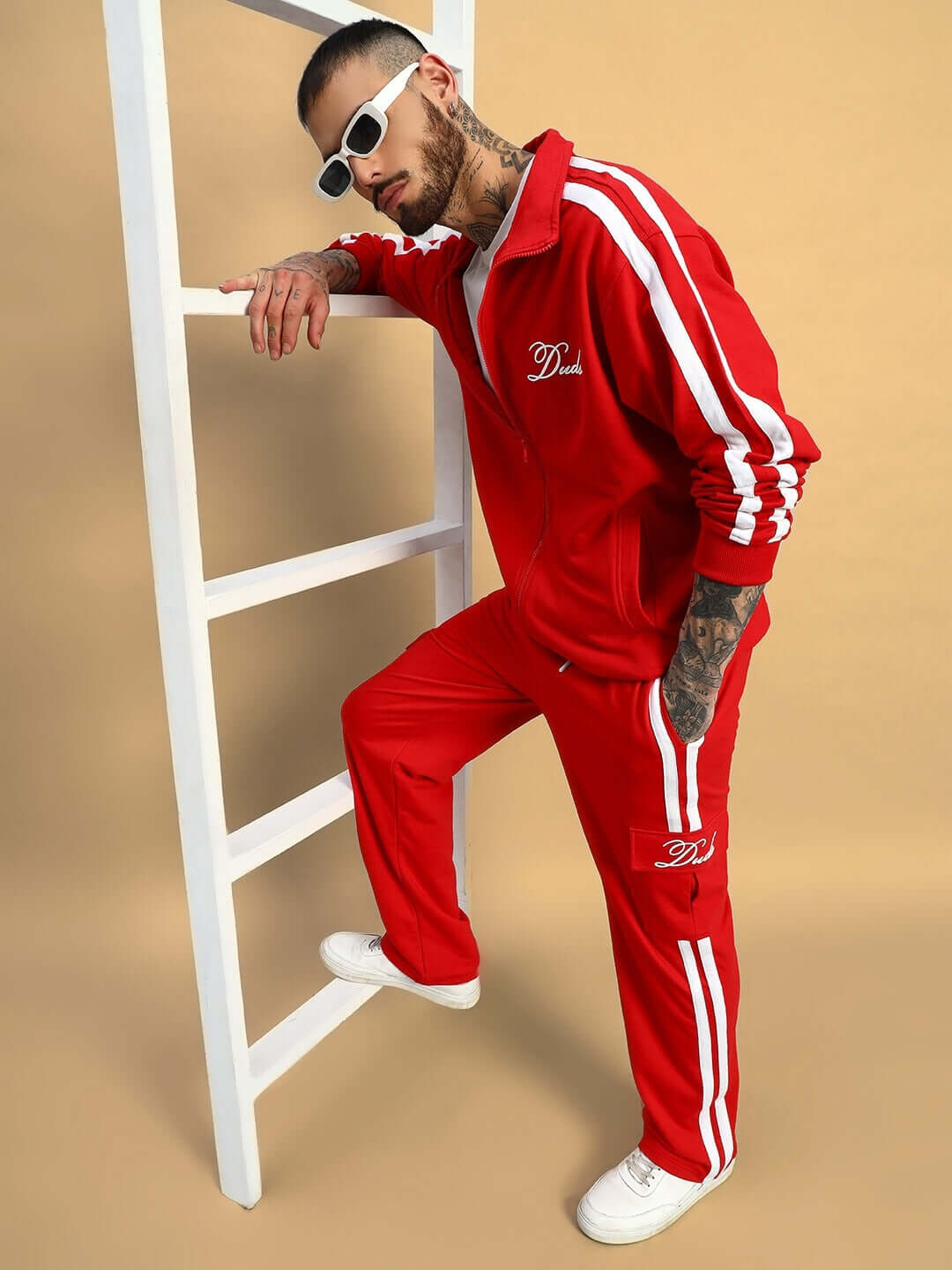 Man wearing a red Scotia jacket with white stripes, standing on a ladder and showcasing sporty fashion.