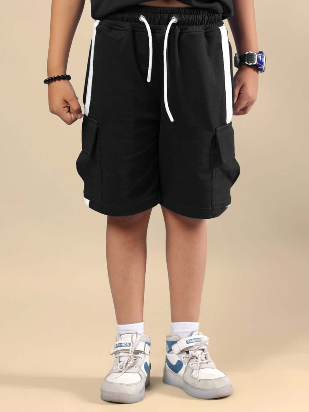 Child wearing SCOTIA SHORTS FOR BOYS & GIRLS BLACK with drawstrings and pockets, shown with sneakers.