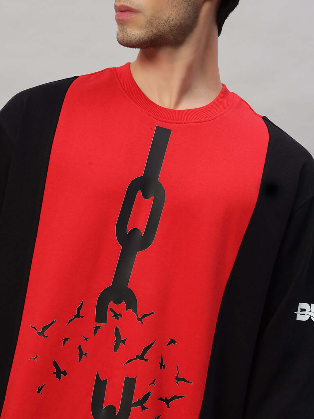 Model wearing SELF-RULE oversized sweatshirt in black-red, featuring chain and bird graphic design; made of premium cotton fabric.
