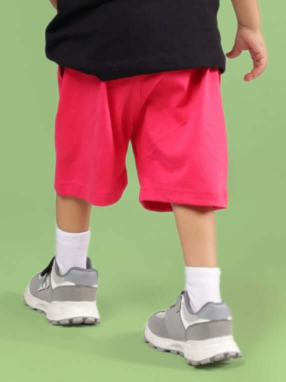 Back view of SESAME SHORTS FOR BOYS & GIRLS PINK worn by child against green background.