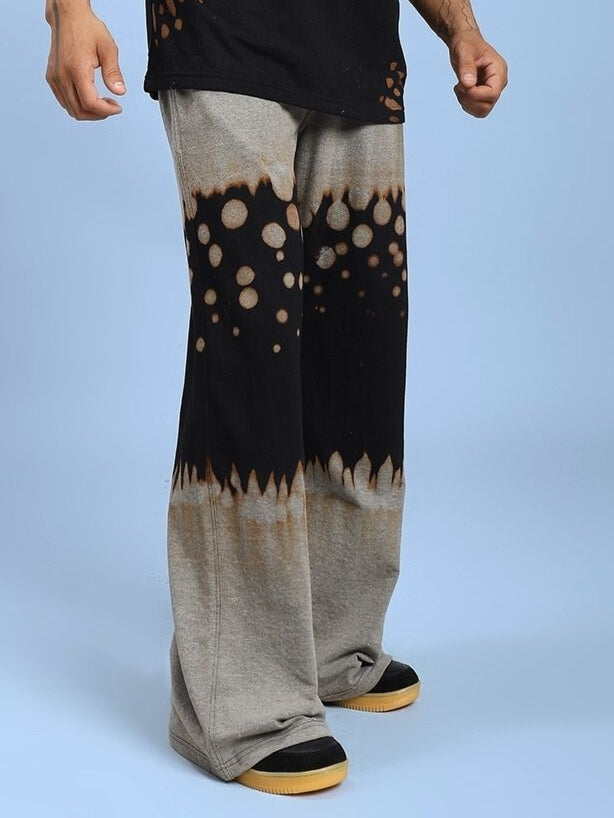 Person wearing SHADOW SWIRL TIE-DYE JOGGER BLACK with unique black pattern, standing against light blue background.