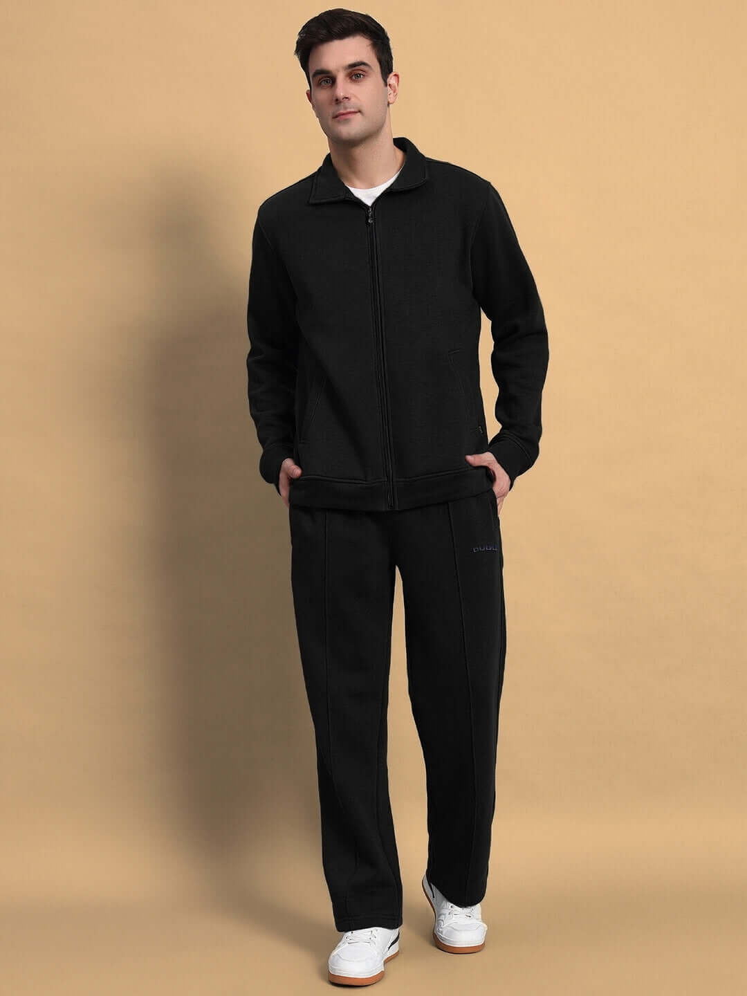 Man wearing black shaggy zipper fleece co-ord set from DUDS, featuring custom fit option, standing against a beige background.