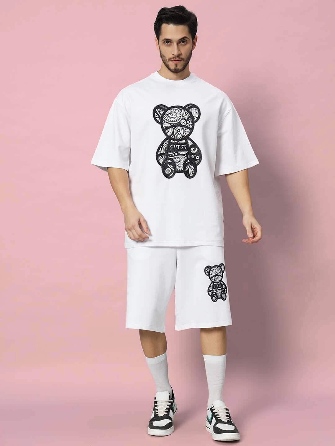 Man wearing white SHIMMY co-ord set with bear print, made of premium cotton French terry Lycra, standing against a pink background.