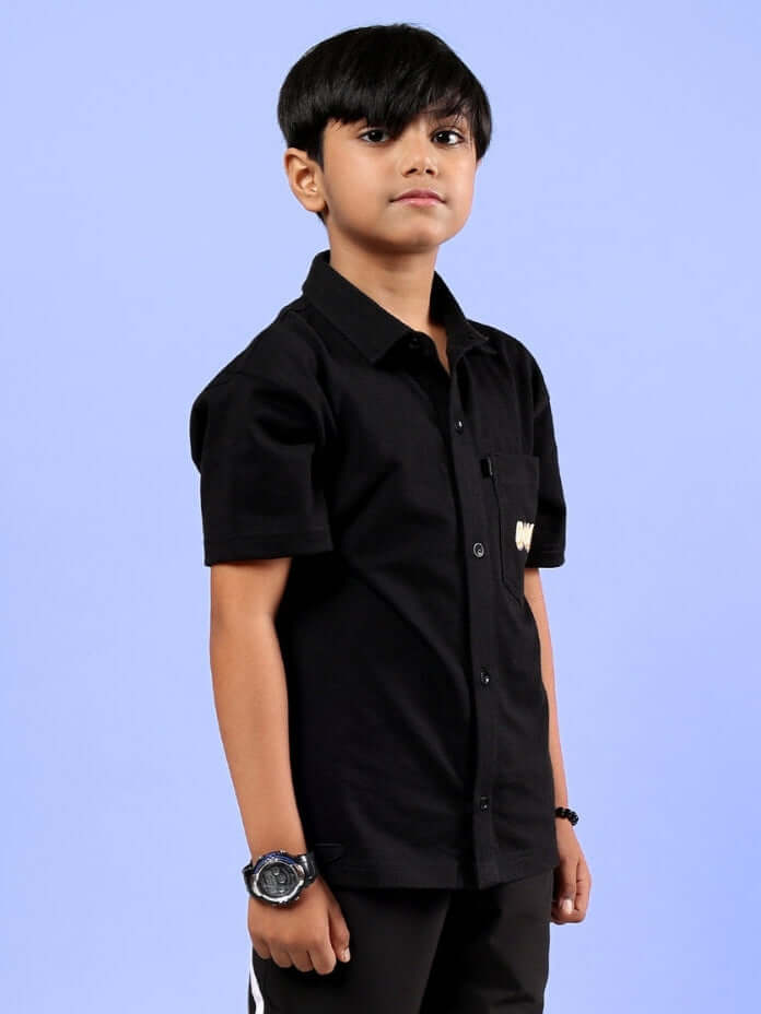 Boy wearing a black Shine Shirt from DUDS, suitable for boys and girls, showcasing stylish short sleeves and front buttons. Perfect for custom fit.