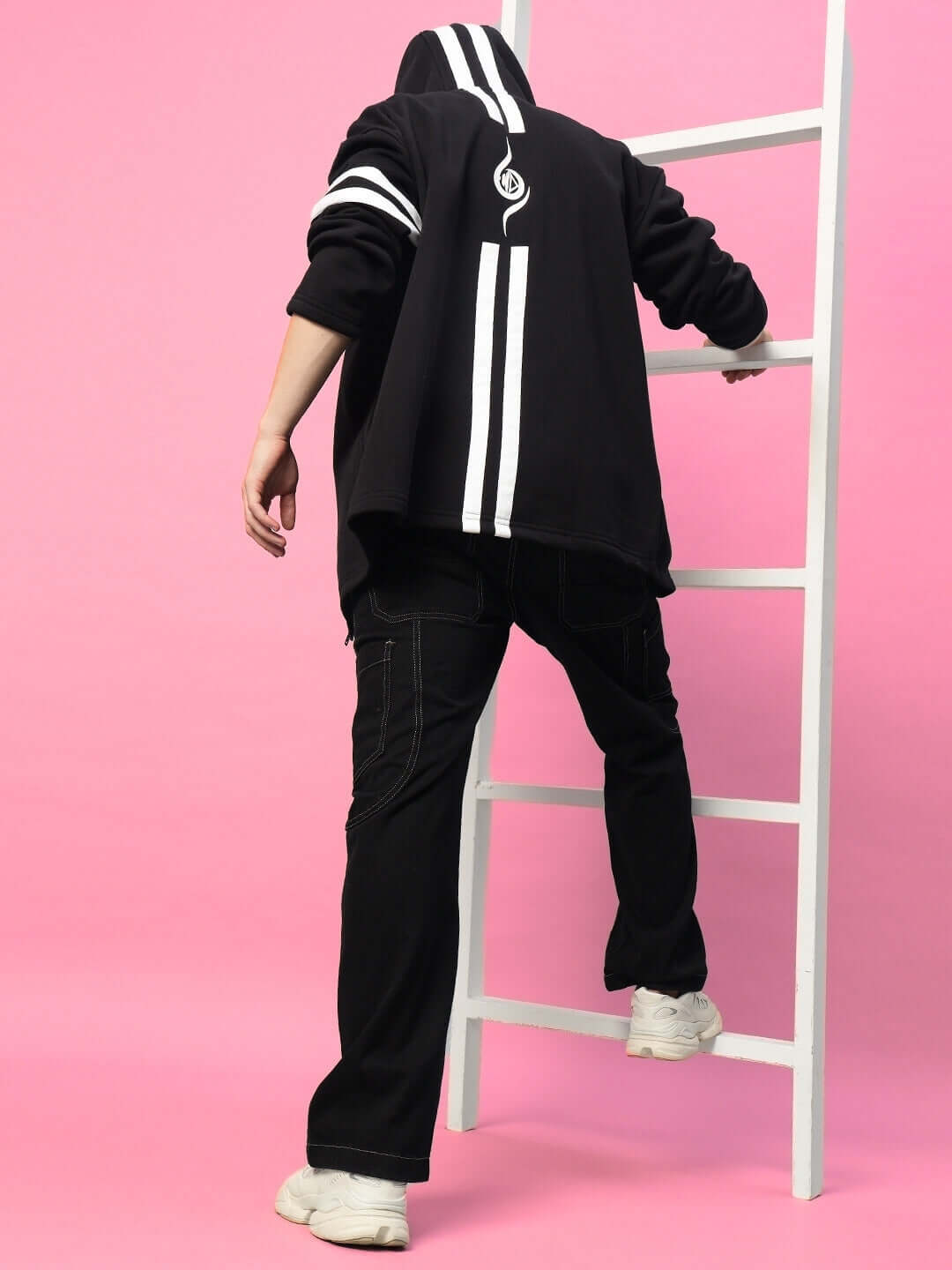 Back view of model wearing SHINOBI ZIPPER LONG LENGTH FLEECE HOODIE BLACK with bold design, standing on ladder