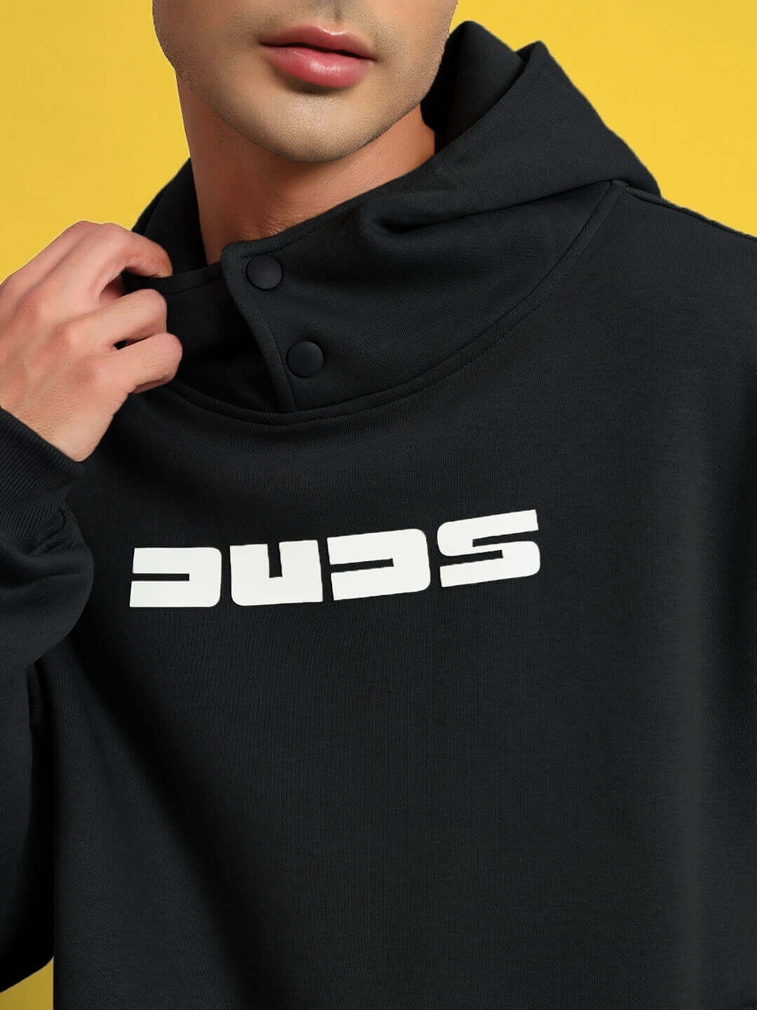 Close-up of WEARDUDS SHOOTER FLEECE CO-ORD BLACK with DUDS logo on a yellow background.