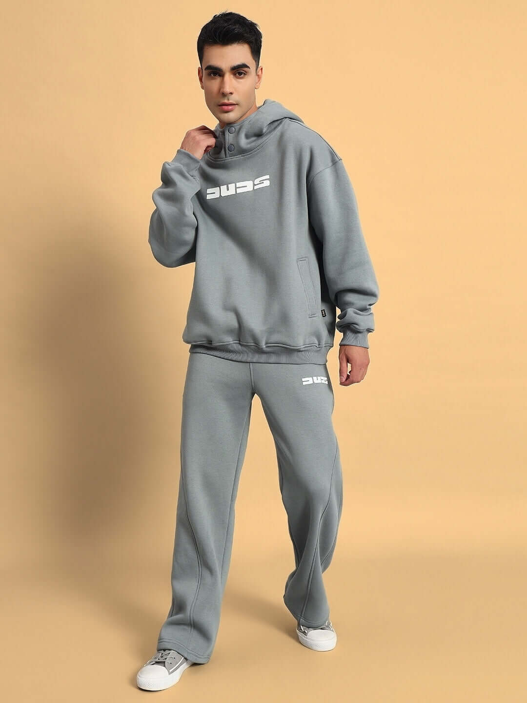 Model wearing grey Shooter Fleece Co-Ord by DUDS, featuring hoodie and pants, available in custom sizes, made to order.