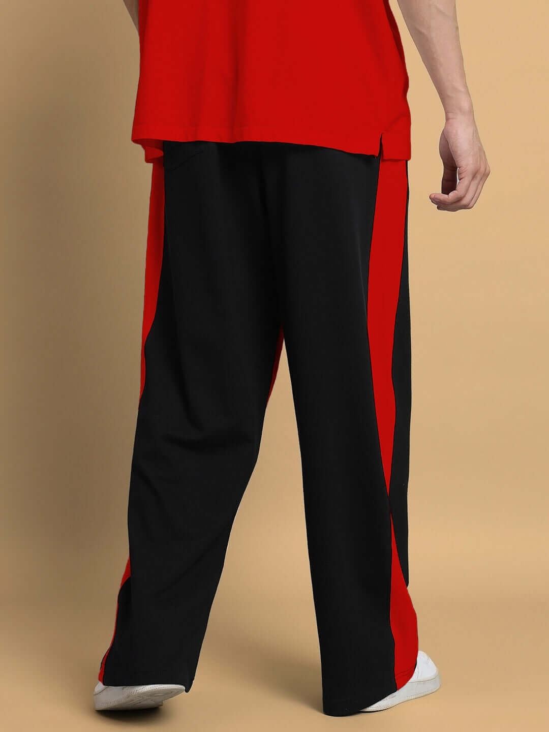 Person wearing SIDE SEAM BAGGY JOGGERS in black and red, standing on a beige background, showcasing the baggy fit and side seam design.