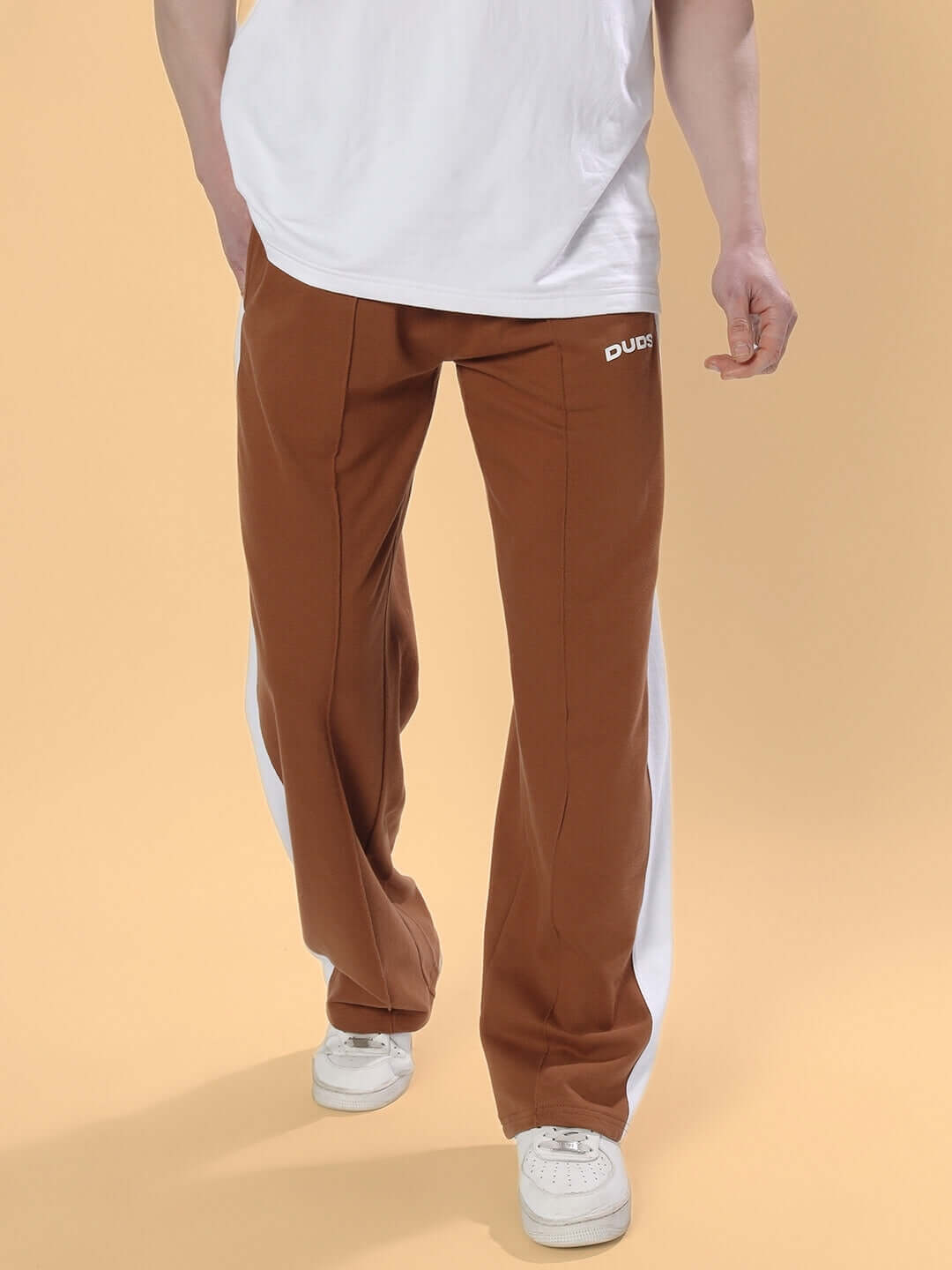 Man wearing brown side seam plated joggers with white sneakers, displaying casual style. Tailored by DUDS, customizable fit available.