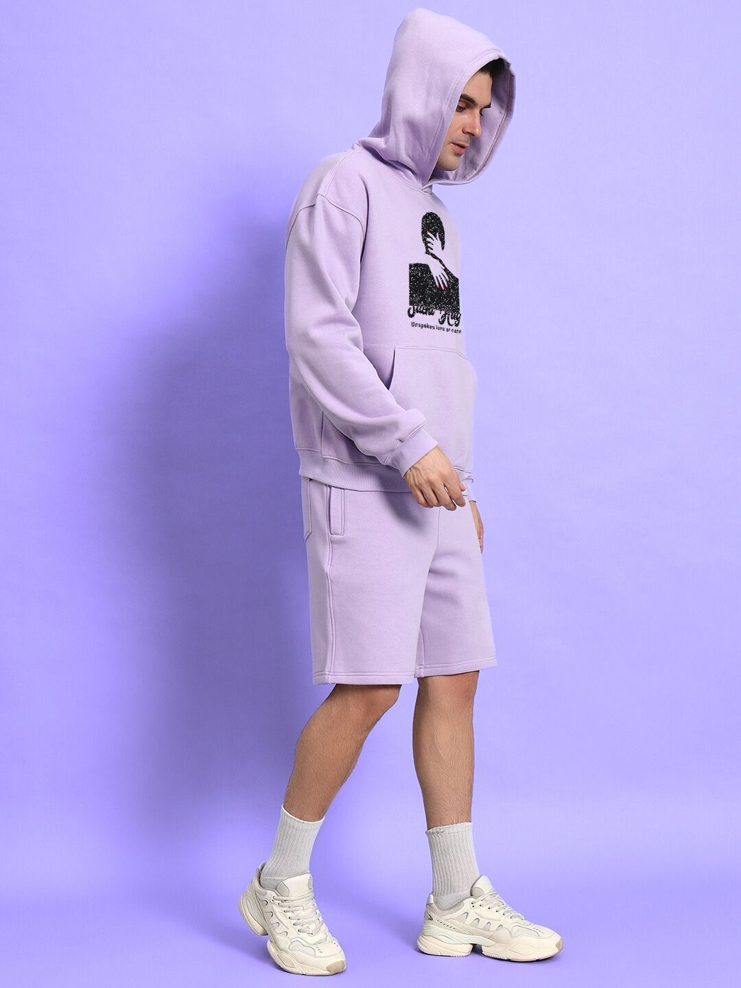 Person wearing SILENT HUG PRINTED FLEECE CO-ORD LILAC set with hoodie and shorts against a lilac background