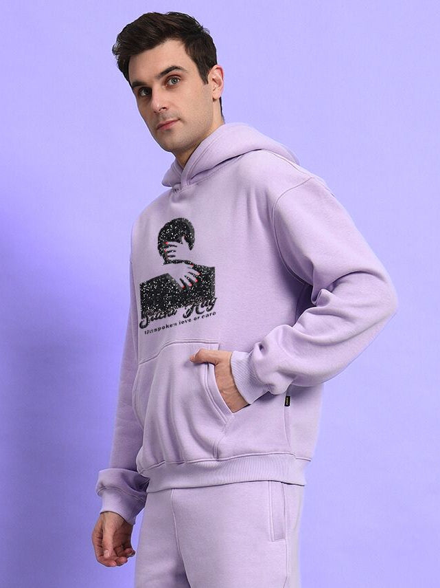 Man wearing SILENT HUG PRINTED FLEECE HOODIE LILAC against purple background.