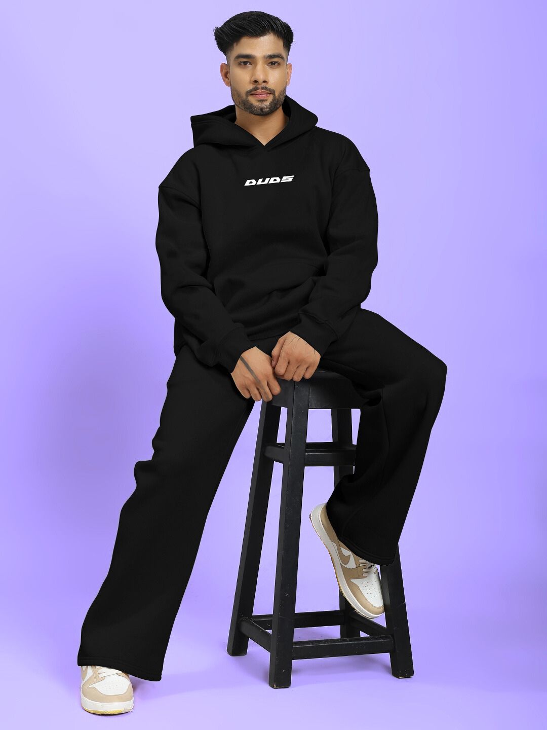 SILVER SURFER FLEECE CO-ORD SET BLACK worn by model sitting on stool, showcasing casual fashion style.