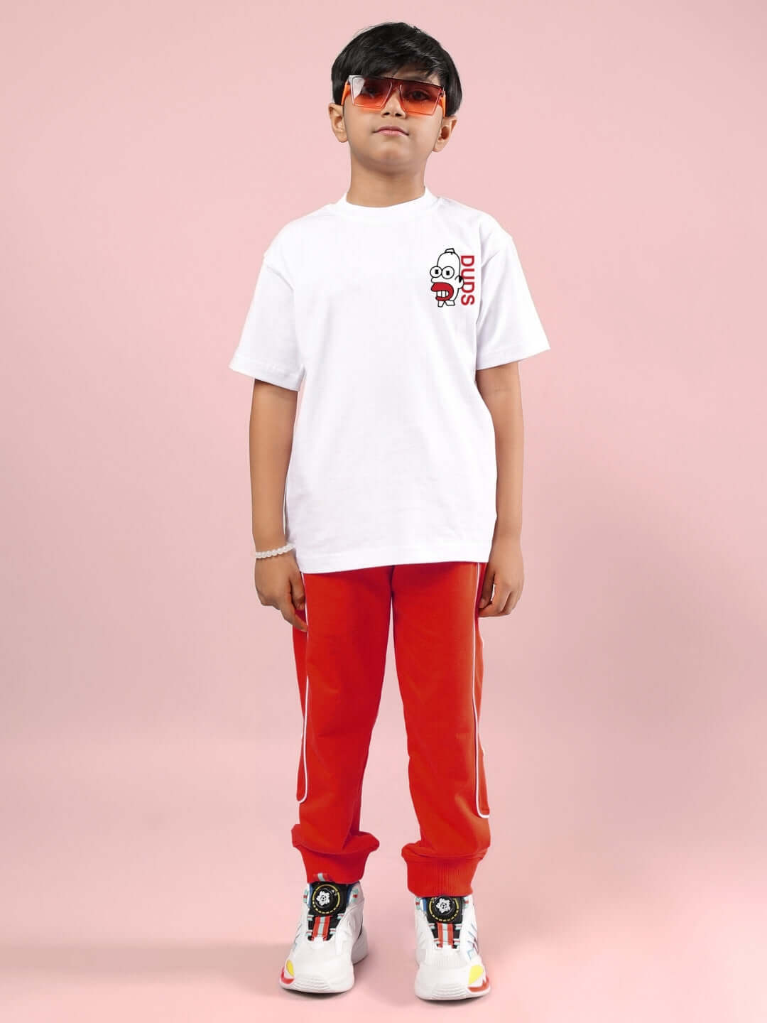 Child wearing SIMPSONS CO-ORD FOR BOYS & GIRLS WHITE-RED with sunglasses and colorful sneakers.