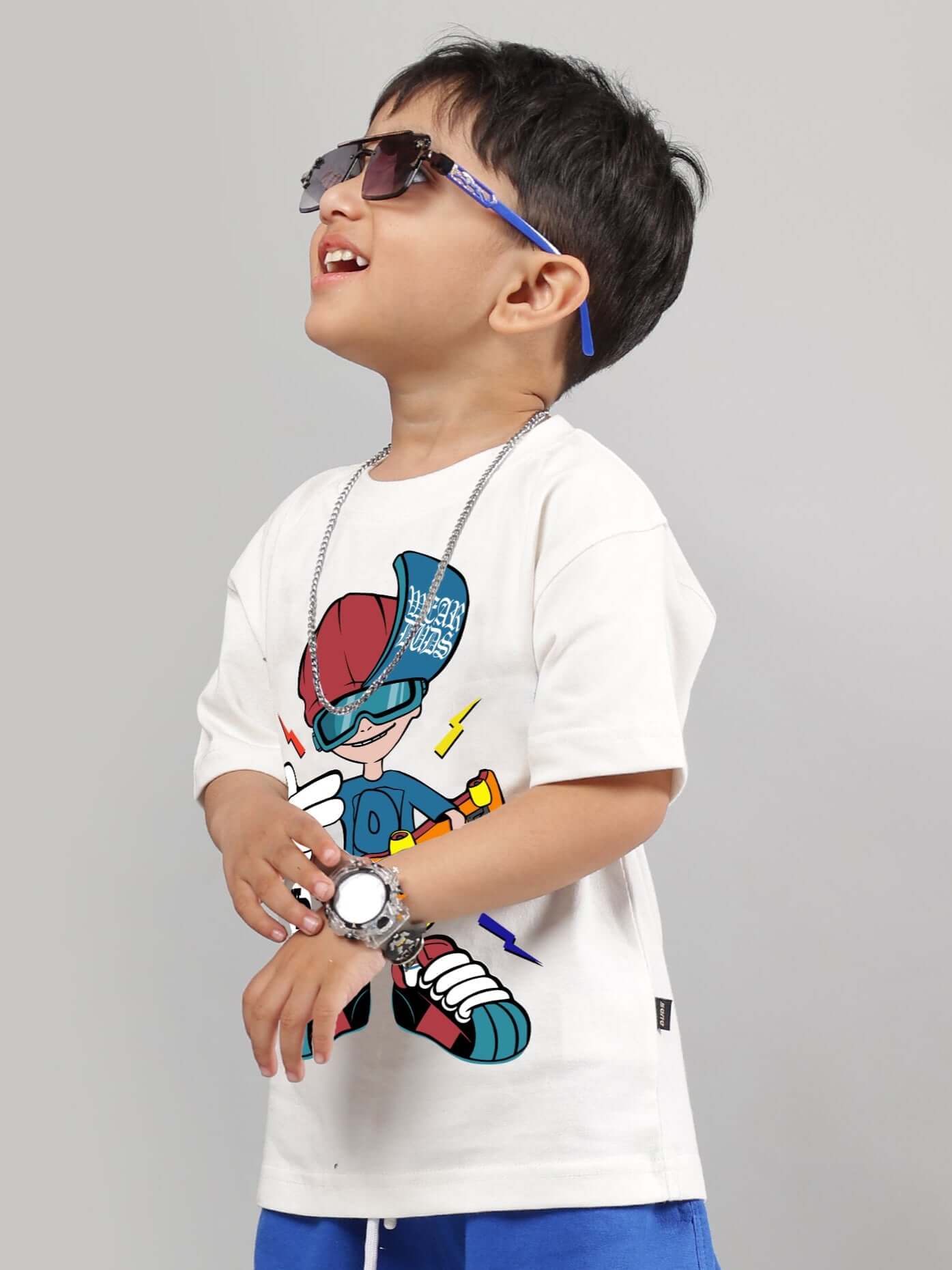 Boy wearing off-white SKATE RIDER T-shirt, featuring a cool graphic design, suitable for boys and girls, styled with sunglasses and accessories.