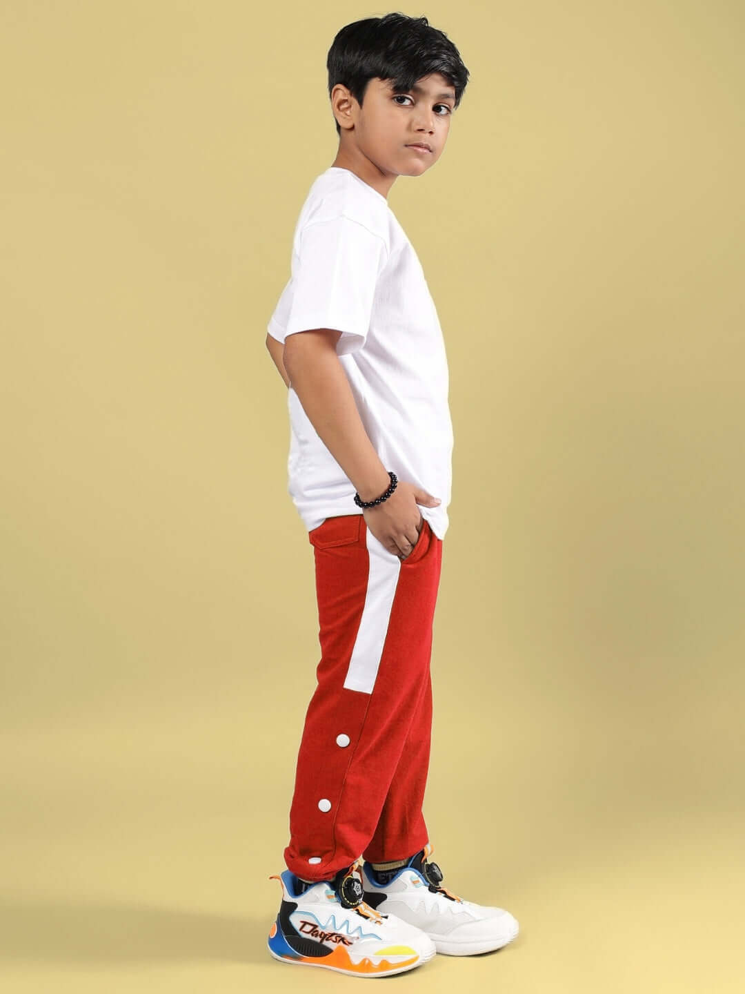 Side view of child wearing SKATER BANANA CO-ORD FOR BOYS & GIRLS WHITE-RED, featuring white shirt and red pants with white stripe, against yellow background