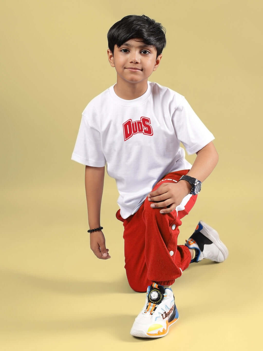 Child wearing DUDS SKATER BANANA CO-ORD FOR BOYS & GIRLS WHITE-RED, featuring a white tee and red pants.