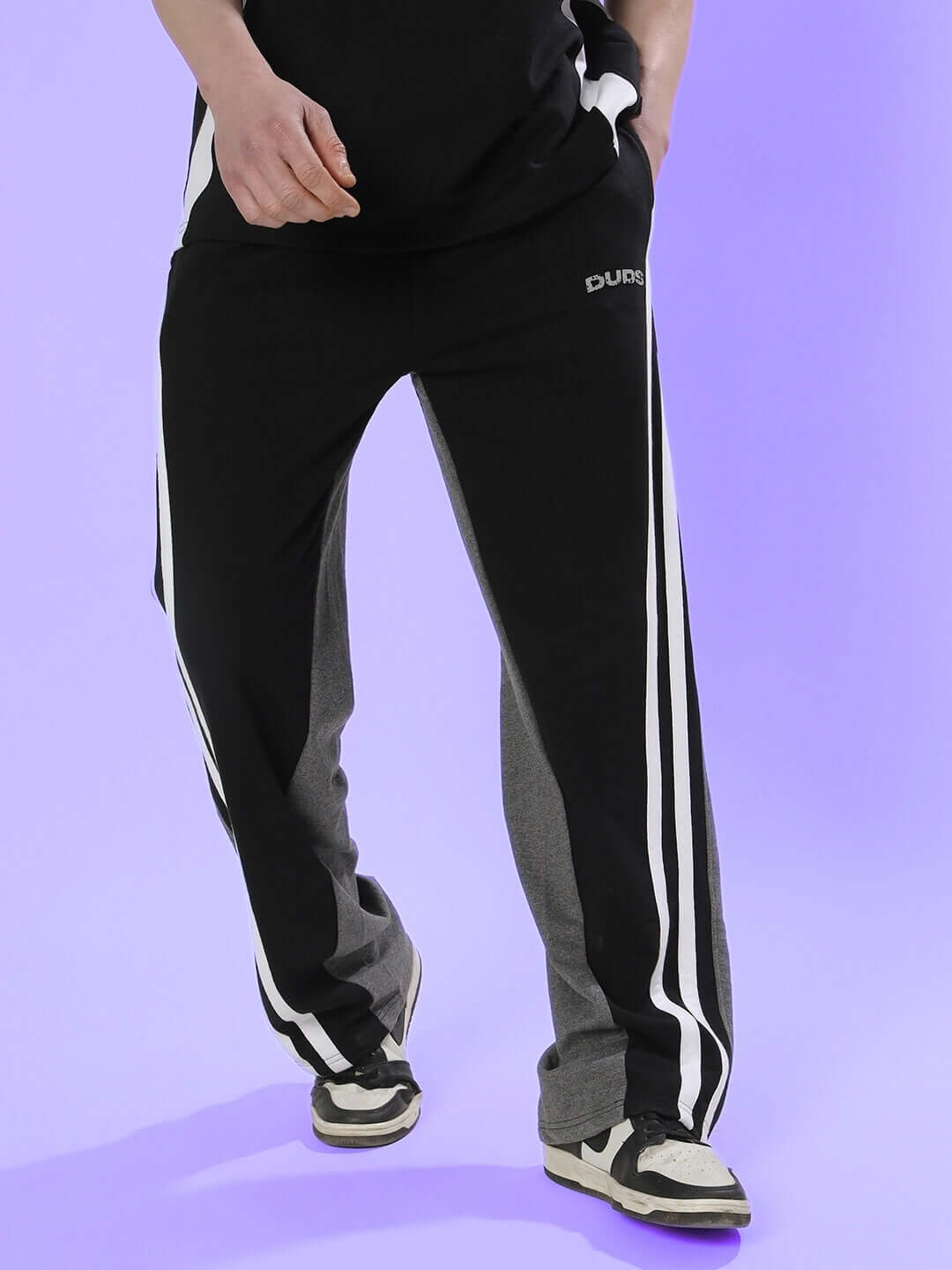 Person wearing DUDS skater Korean baggy joggers in black grey with sporty stripes.