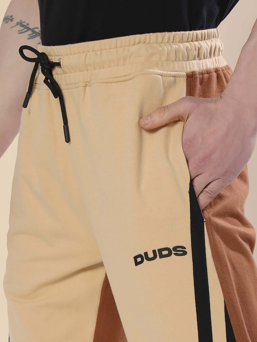 Young man wearing SKATER KOREAN BAGGY JOGGERS in cream brown with DUDS logo, showcasing casual fit and style.