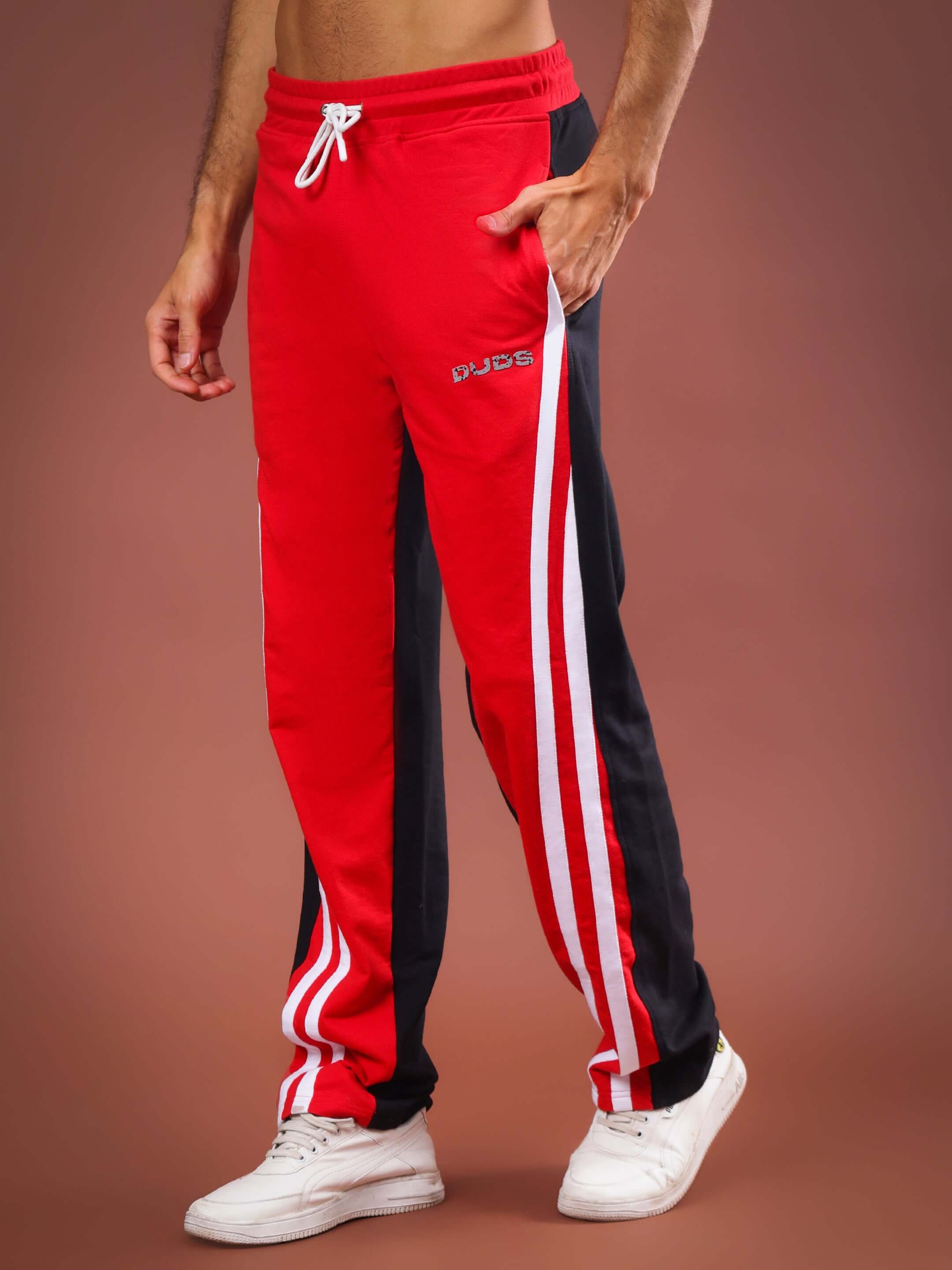 Red and black skater Korean baggy joggers with white stripes, featuring adjustable waist, designed by DUDS, shown on male model with white shoes.