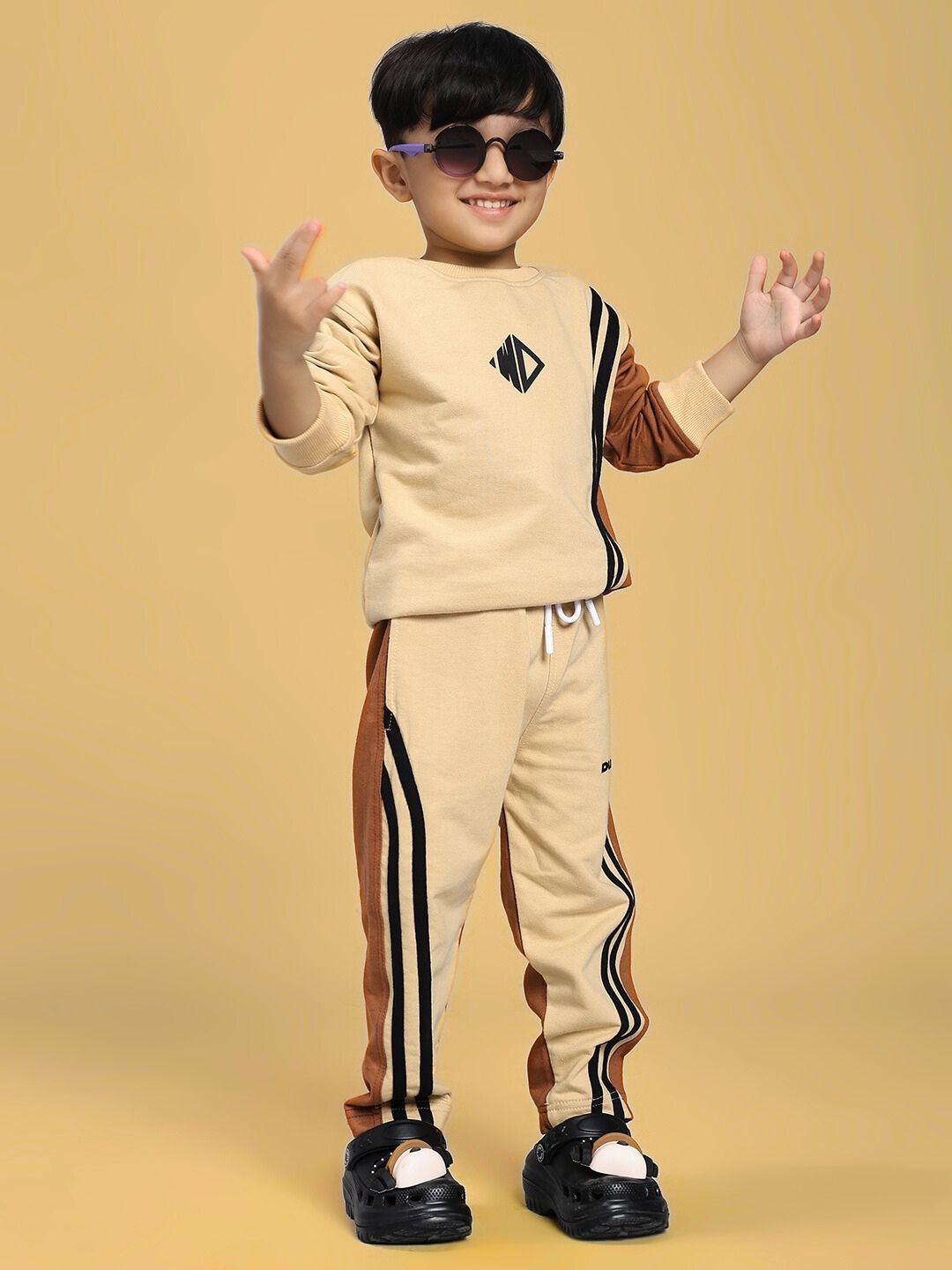 Child wearing SKATER KOREAN CO-ORD FOR BOYS AND GIRLS CREAM BROWN outfit with trendy graphics on a yellow background.