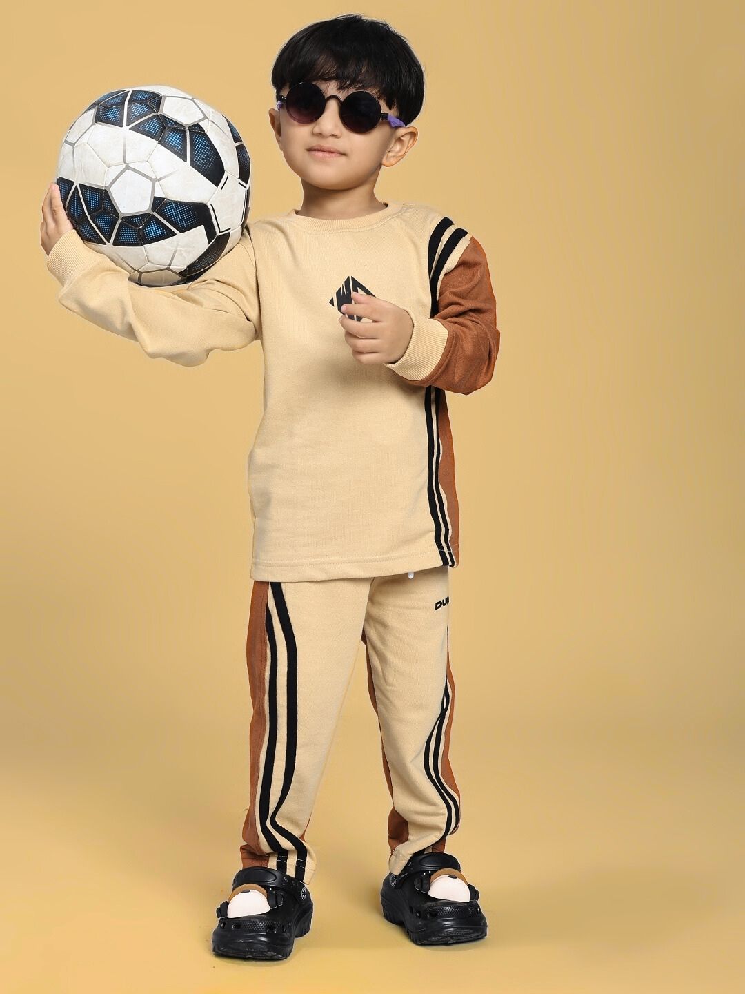 Child wearing SKATER KOREAN CO-ORD FOR BOYS AND GIRLS CREAM BROWN, holding a soccer ball.
