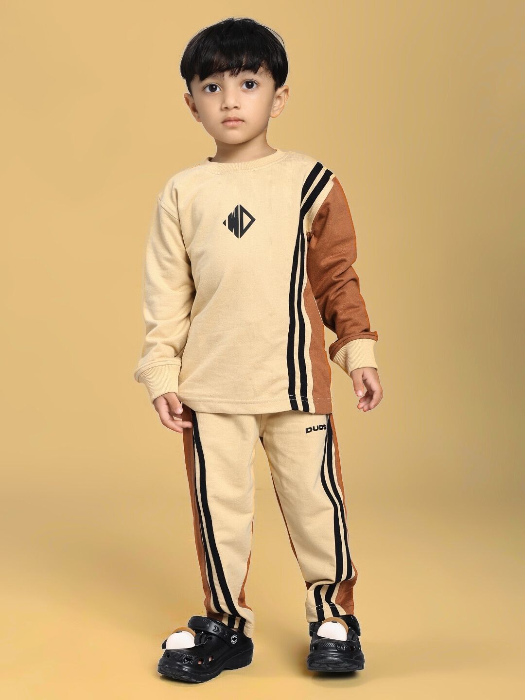 Child wearing SKATER KOREAN CO-ORD FOR BOYS AND GIRLS CREAM BROWN, featuring trendy graphics and comfortable design in cream and brown hues.