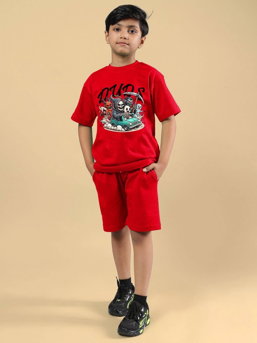 Boy wearing SKELETON RIDER CAR PRINT CO-ORD FOR BOYS AND GIRLS RED with a car graphic, standing with hands in pockets.