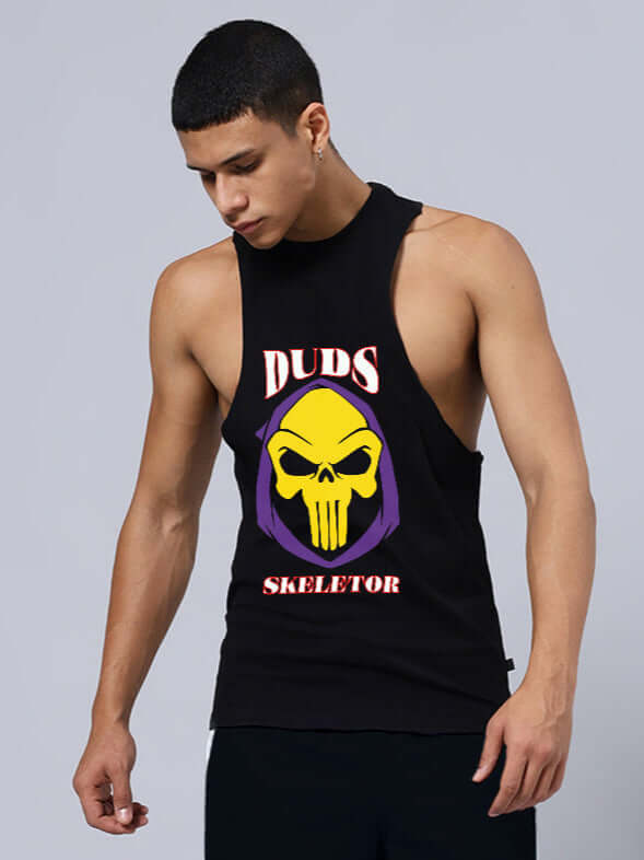 Man wearing SKELETOR PRINTED GYM T-SHIRT BLACK, showcasing custom fit options by DUDS, sleeveless design, on a gray background.